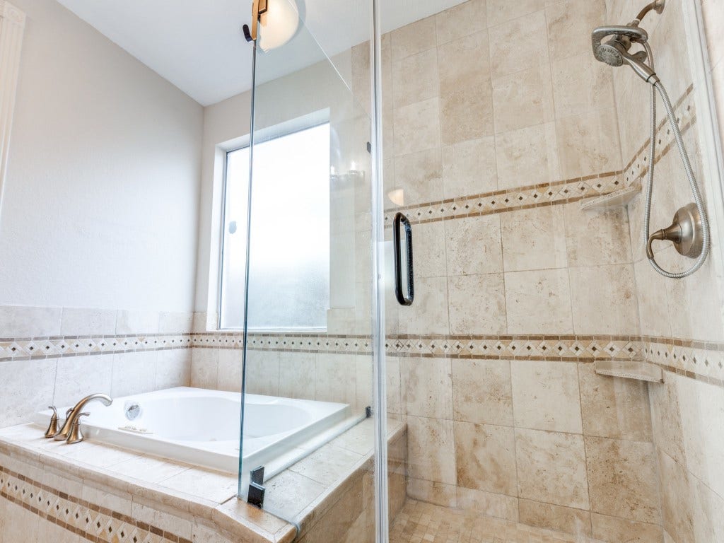 2811 Princeton Street, Houston, TX 77009 This bathroom features a luxurious glass-enclosed shower with elegant tile work and a nearby soaking tub, providing a spa-like atmosphere.