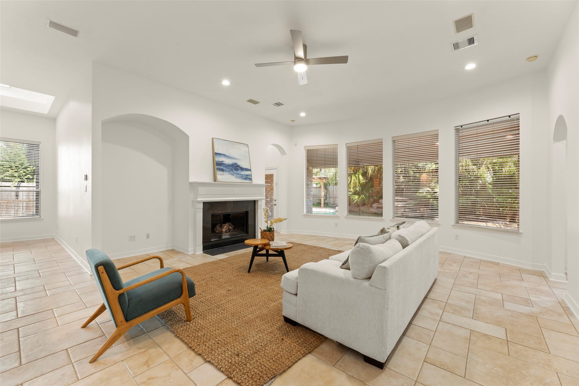 1211 Sterling Court, Katy, TX 77494 Bright and inviting living room featuring a cozy fireplace, large windows with garden views, and elegant tile flooring.