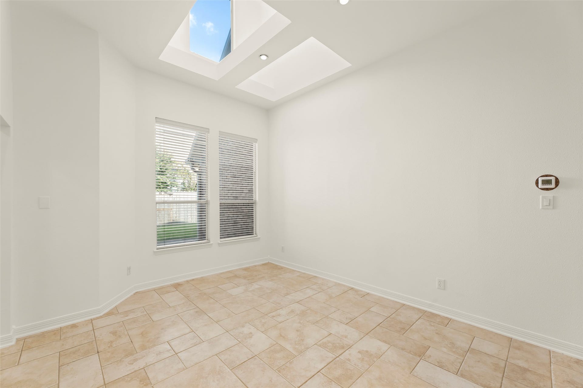 1211 Sterling Court, Katy, TX 77494 Bright and airy room with skylights, large windows, and elegant tile flooring, perfect for a cozy breakfast area or home office.