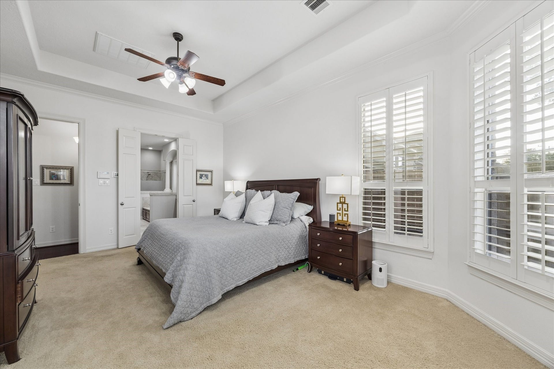 The primary suite has room for seating, large furniture, and overlooks the back yard and greenbelt beyond.