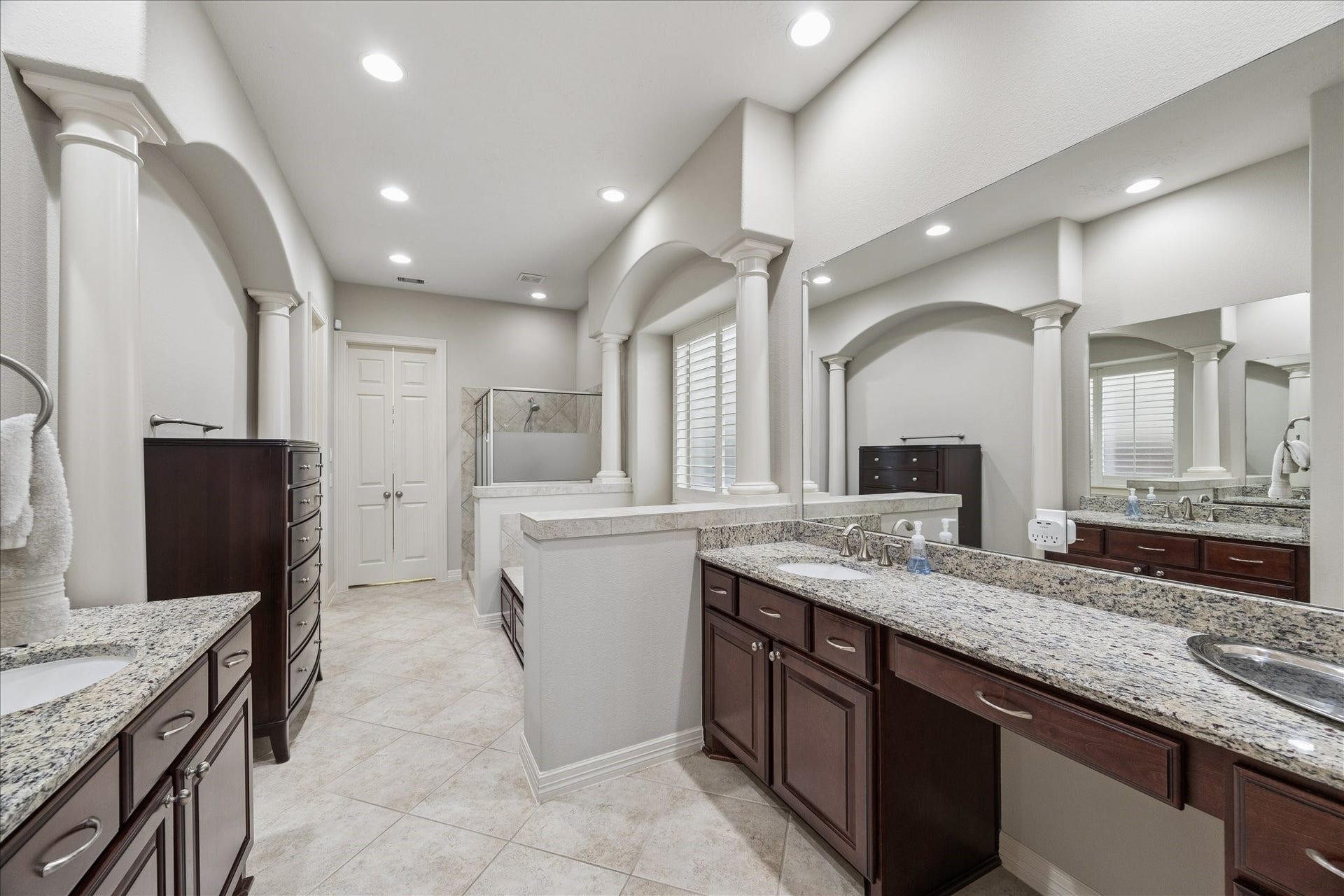 This is a perfect view of the en suite bath with separate vanities, soaking tub, large shower and closet beyond.