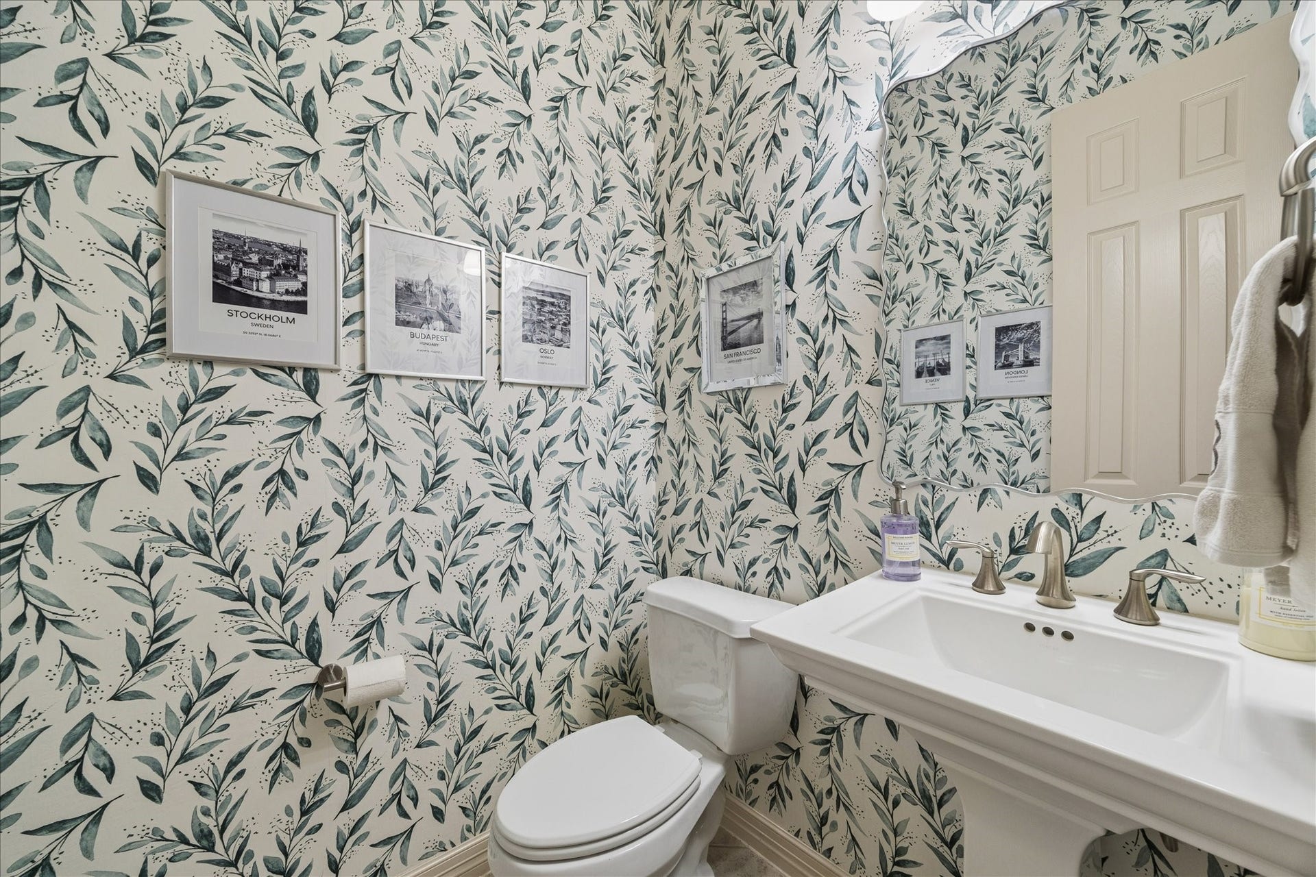 The half bath with a pedestal sink and charming wallpaper.
