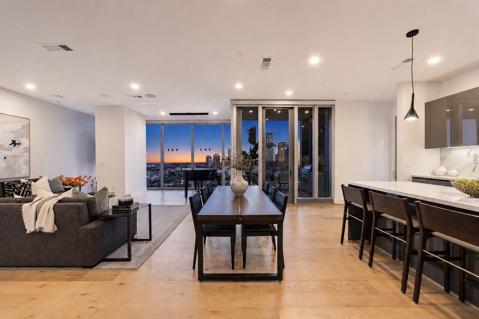 his modern open-concept living space features a spacious layout with hardwood floors, a sleek kitchen with an island, and a cozy living area. Floor-to-ceiling windows offer stunning cityscape views, enhancing the bright and airy ambiance.