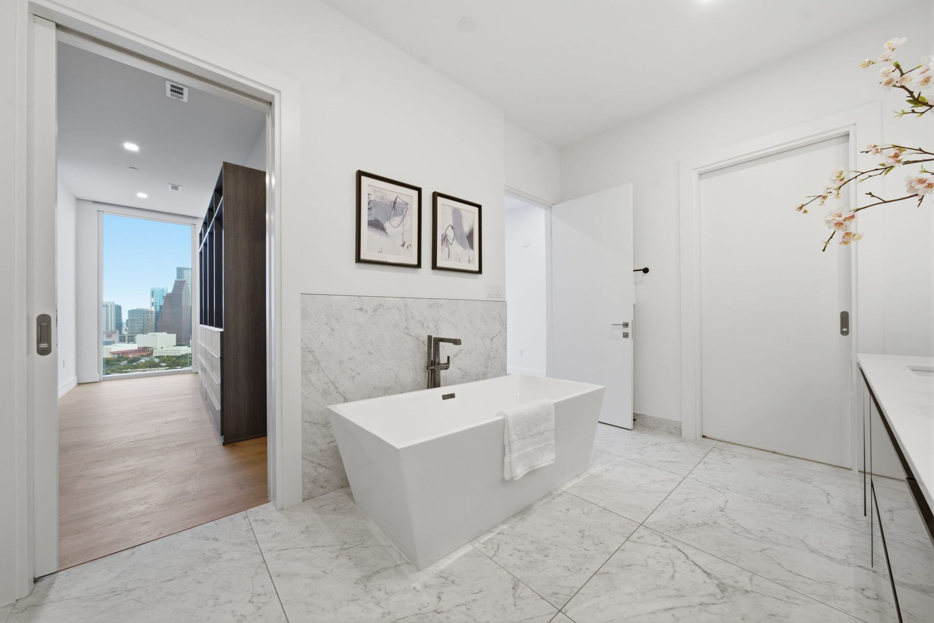 A marble clad primary bath that feels more like a luxury hotel spa than a private residence.
Custom walk in closet designed by California Closets, featuring a floor to ceiling shoe display, and rare Downtown Houston skyline views that bring natural light and luxury into your daily routine.