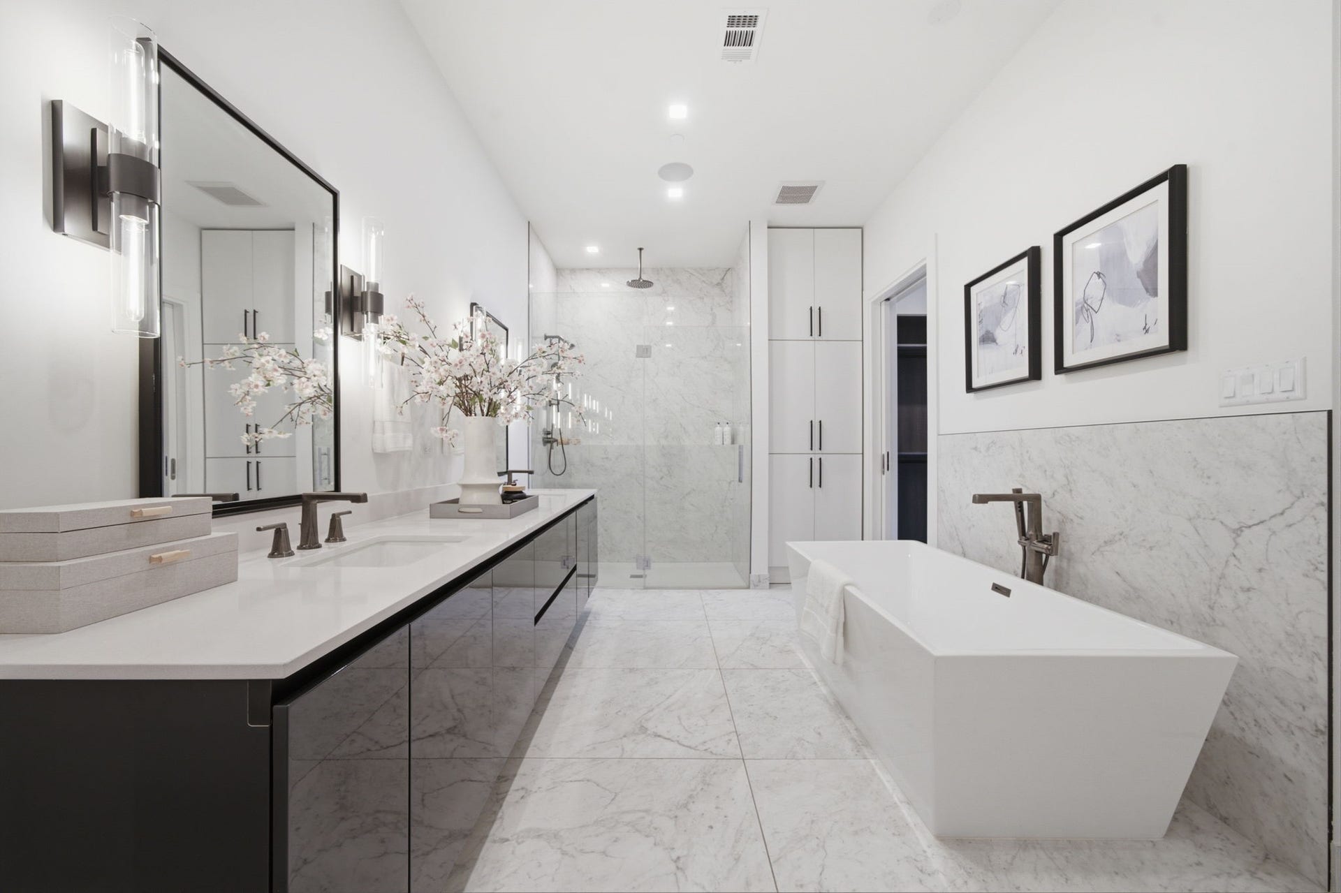 A spa worthy primary bath featuring marble finishes, a soaking tub, and oversized walk in shower.