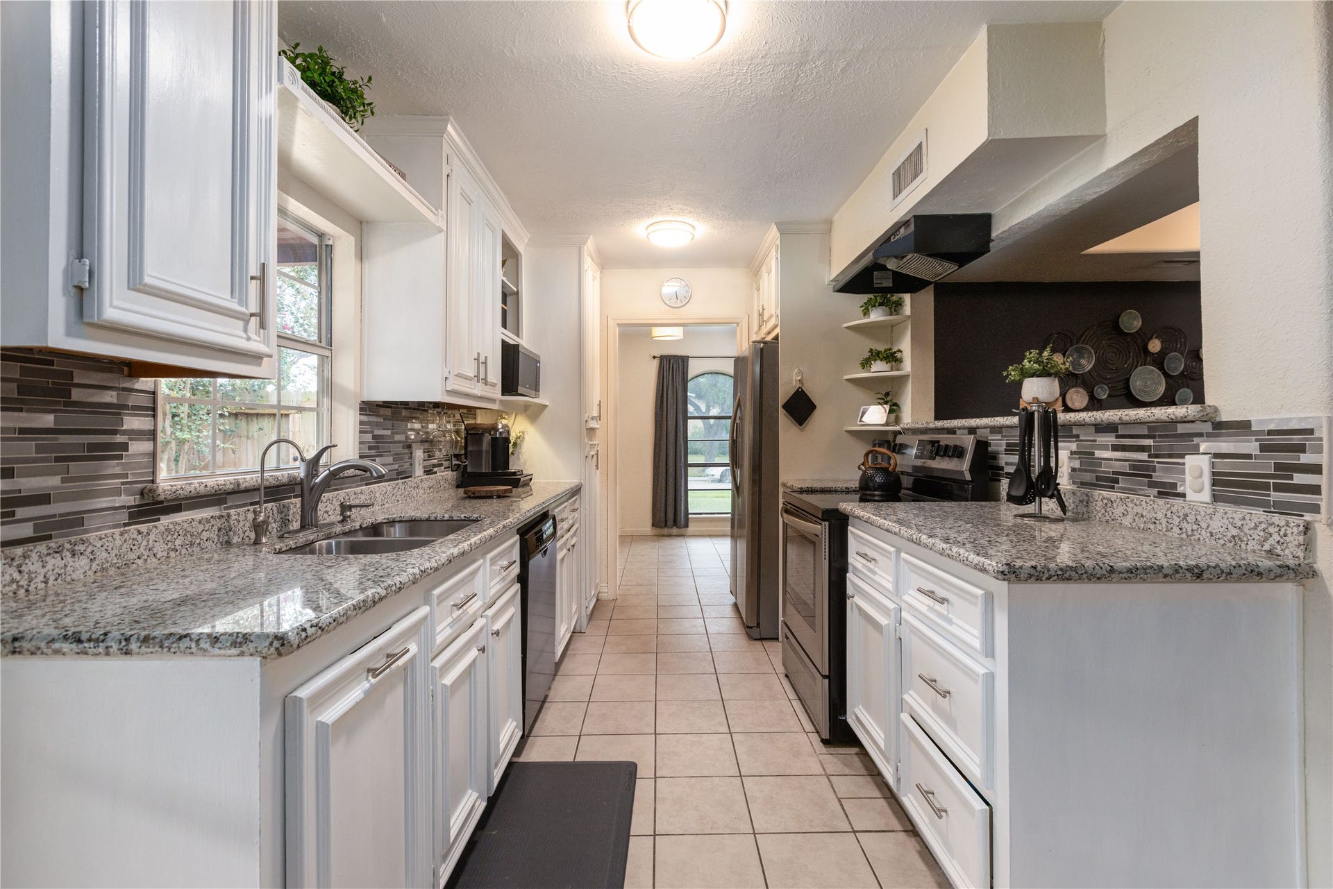 14007 Lorne Drive, Houston, TX 77049 Charming galley kitchen with sleek granite countertops, modern tile backsplash, and ample cabinetry, offering a bright and functional space for cooking and entertaining.