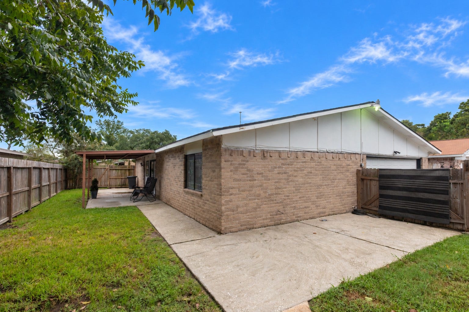 14007 Lorne Drive, Houston, TX 77049 Charming backyard features a covered patio perfect for outdoor relaxation, surrounded by a privacy fence and lush greenery.