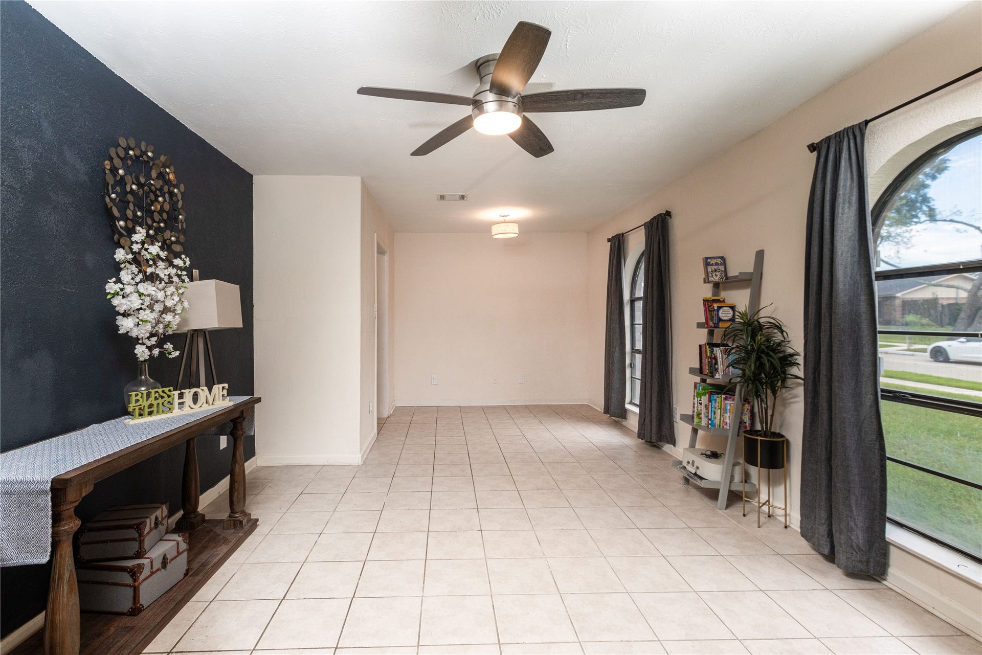 14007 Lorne Drive, Houston, TX 77049 Bright and airy room with large arched windows, stylish tile flooring, and a modern ceiling fan.