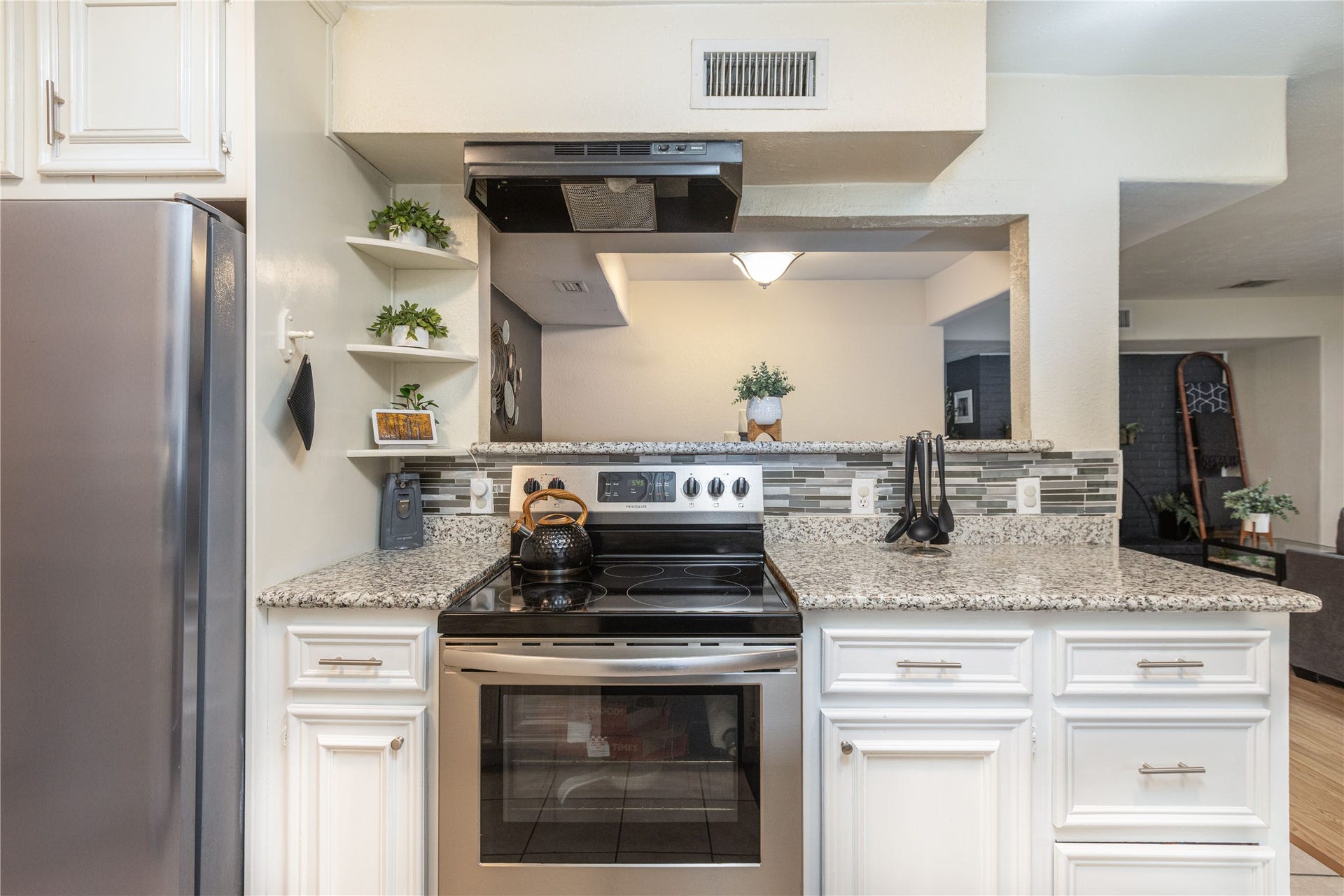 14007 Lorne Drive, Houston, TX 77049 Modern kitchen with sleek stainless steel appliances, granite countertops, and stylish open shelving for a functional and elegant cooking space.