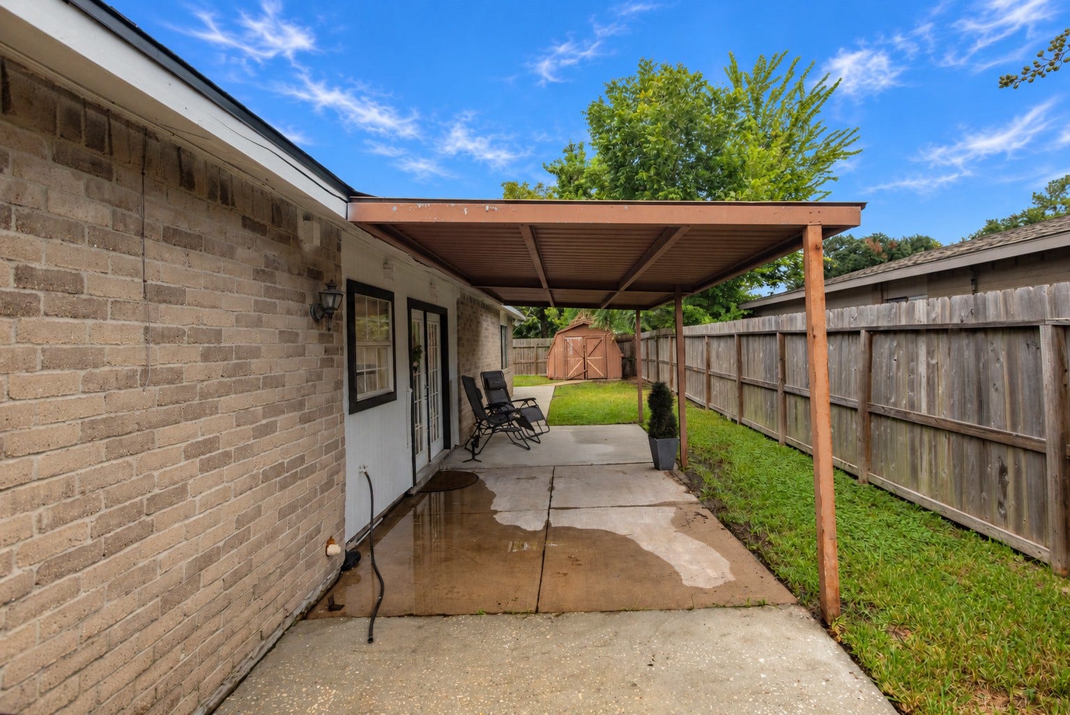 14007 Lorne Drive, Houston, TX 77049 Charming covered patio area with cozy seating, perfect for relaxing, leads to a private fenced yard with a storage shed.