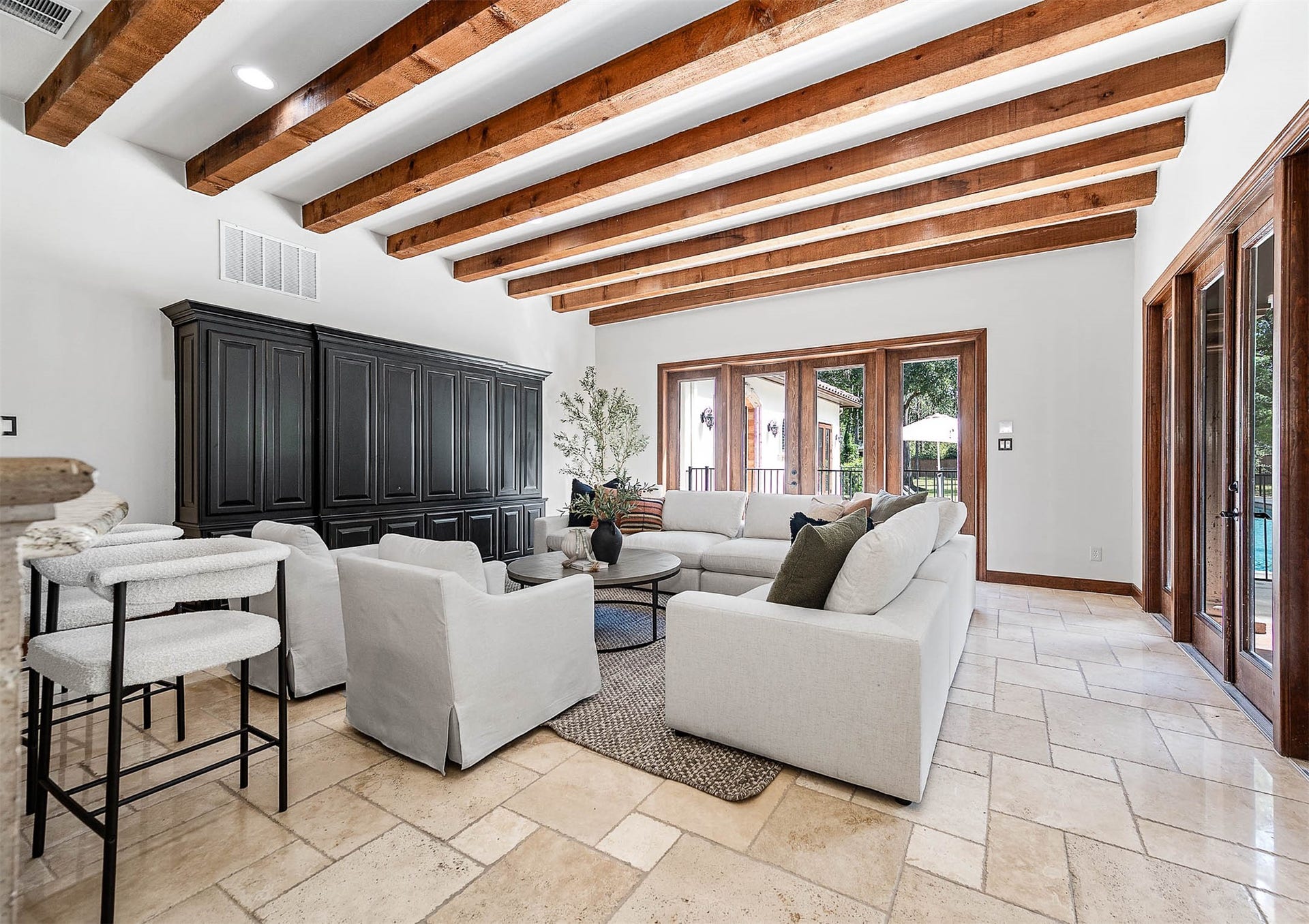 The family room features exposed wood beams, French doors to the backyard, and an open flow to the kitchen and wine bar.
