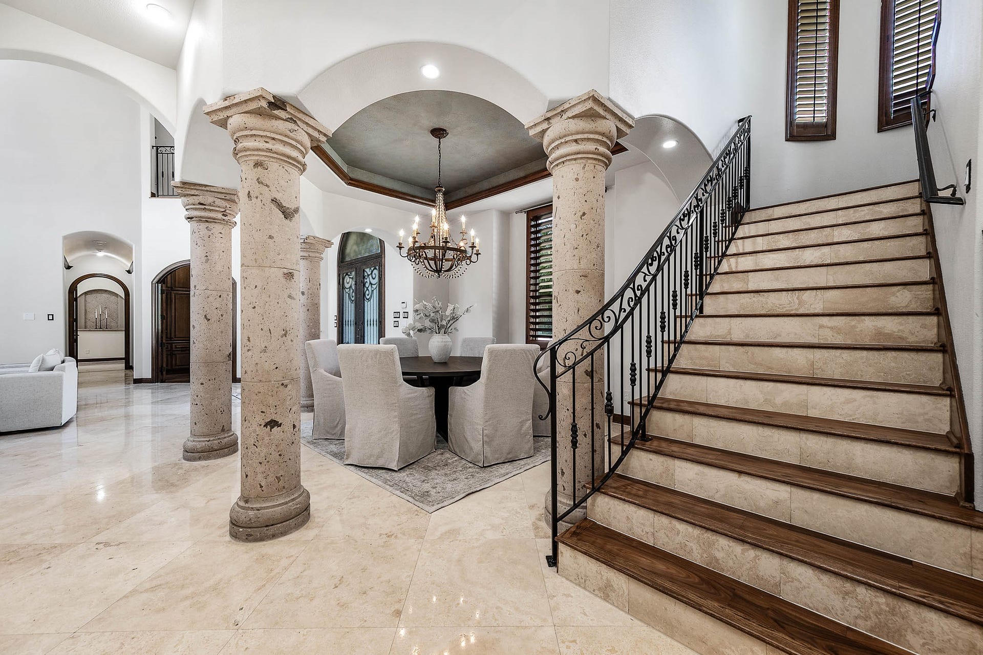 Cantera stone columns and arched openings frame the formal dining room and the staircase leading to the second floor.