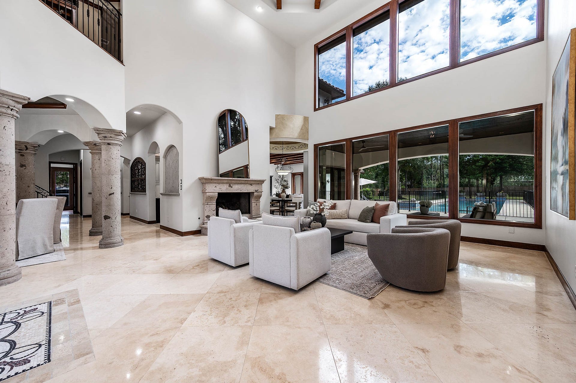 The formal living room features soaring ceilings and double-story windows overlooking the grounds, filling the space with natural light.