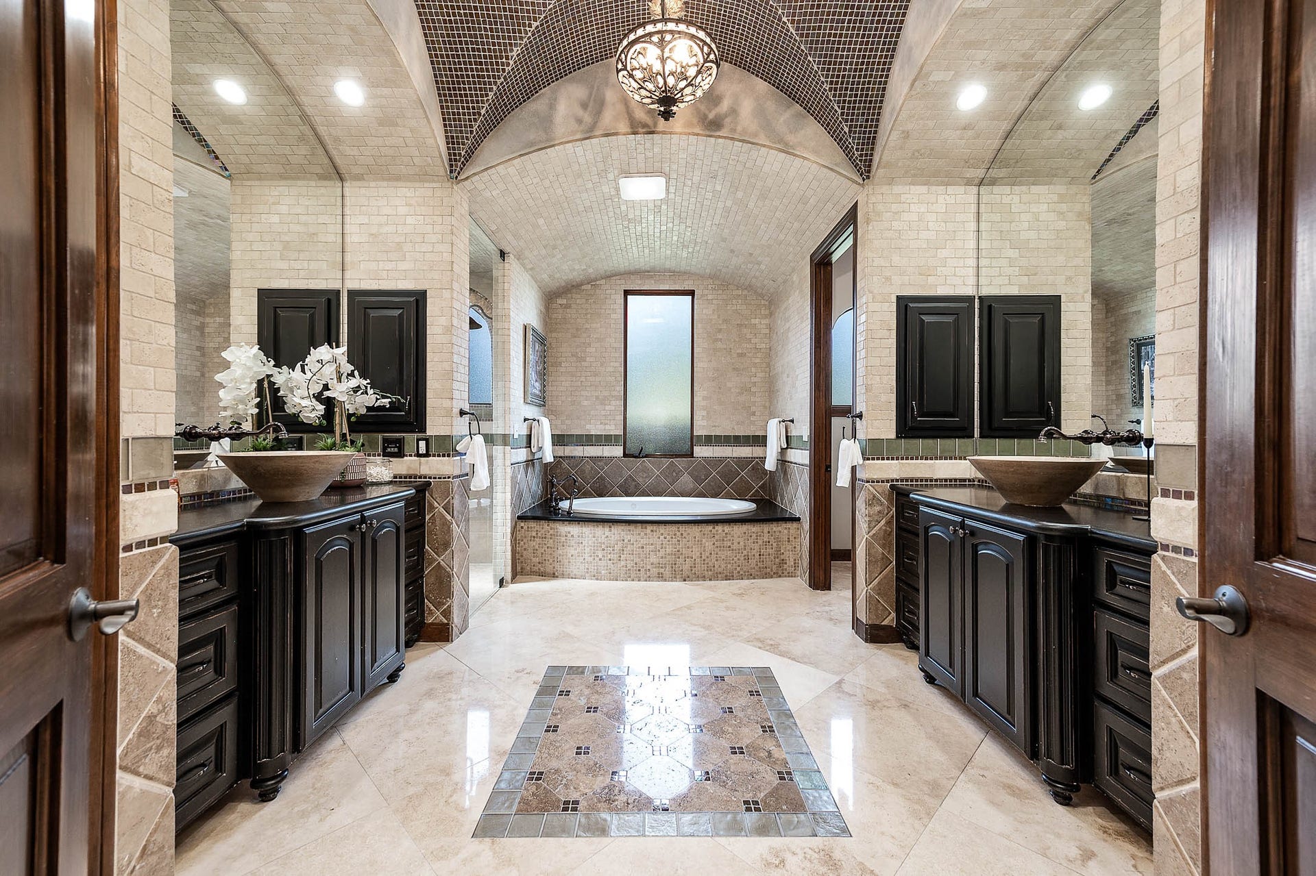 The spa-like primary bath features dual vanities with vessel sinks beneath a barrel-vaulted tile ceiling.