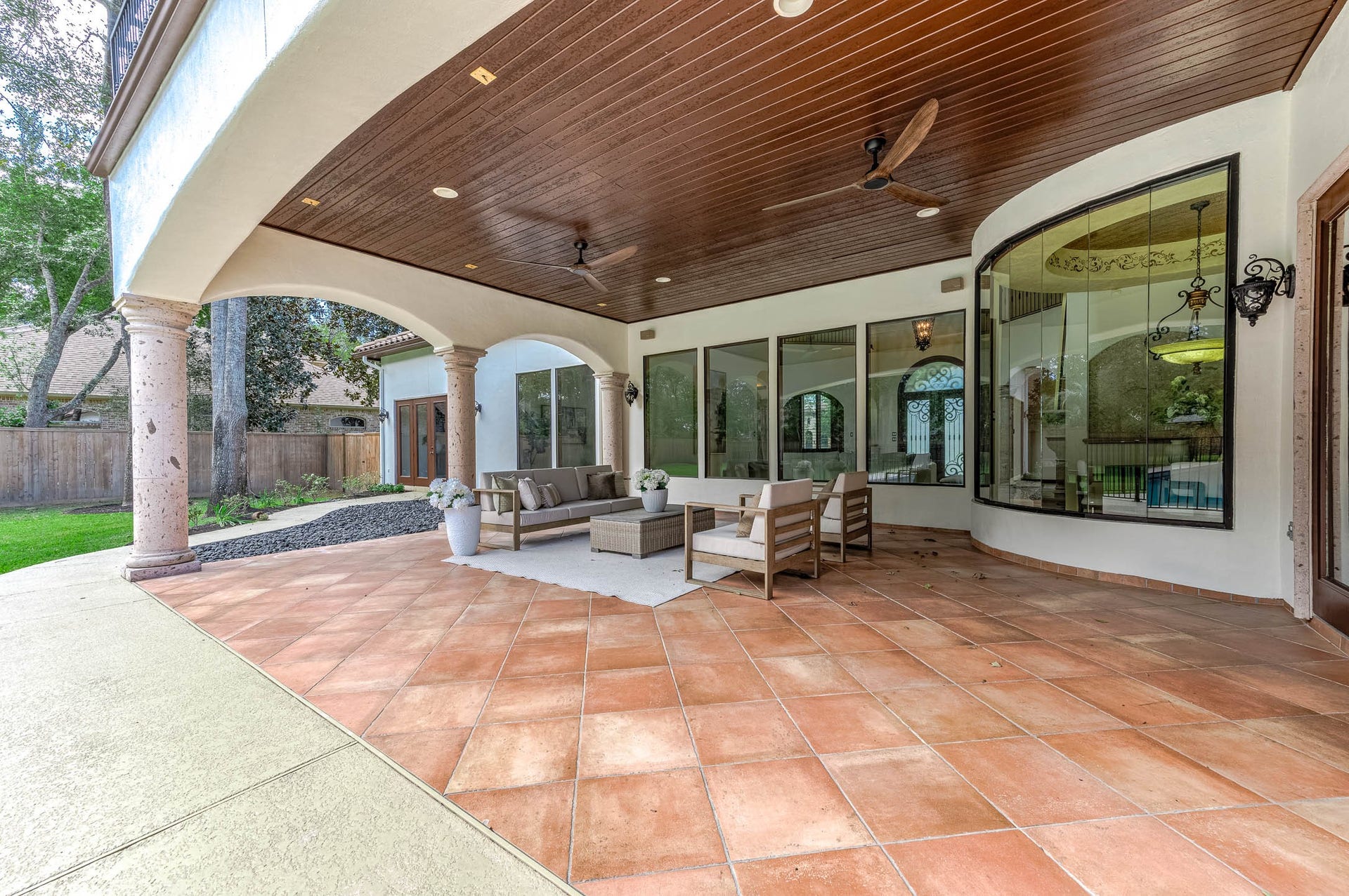 The covered patio features a stained wood ceiling and Cantera stone columns, extending the home's living space outdoors.