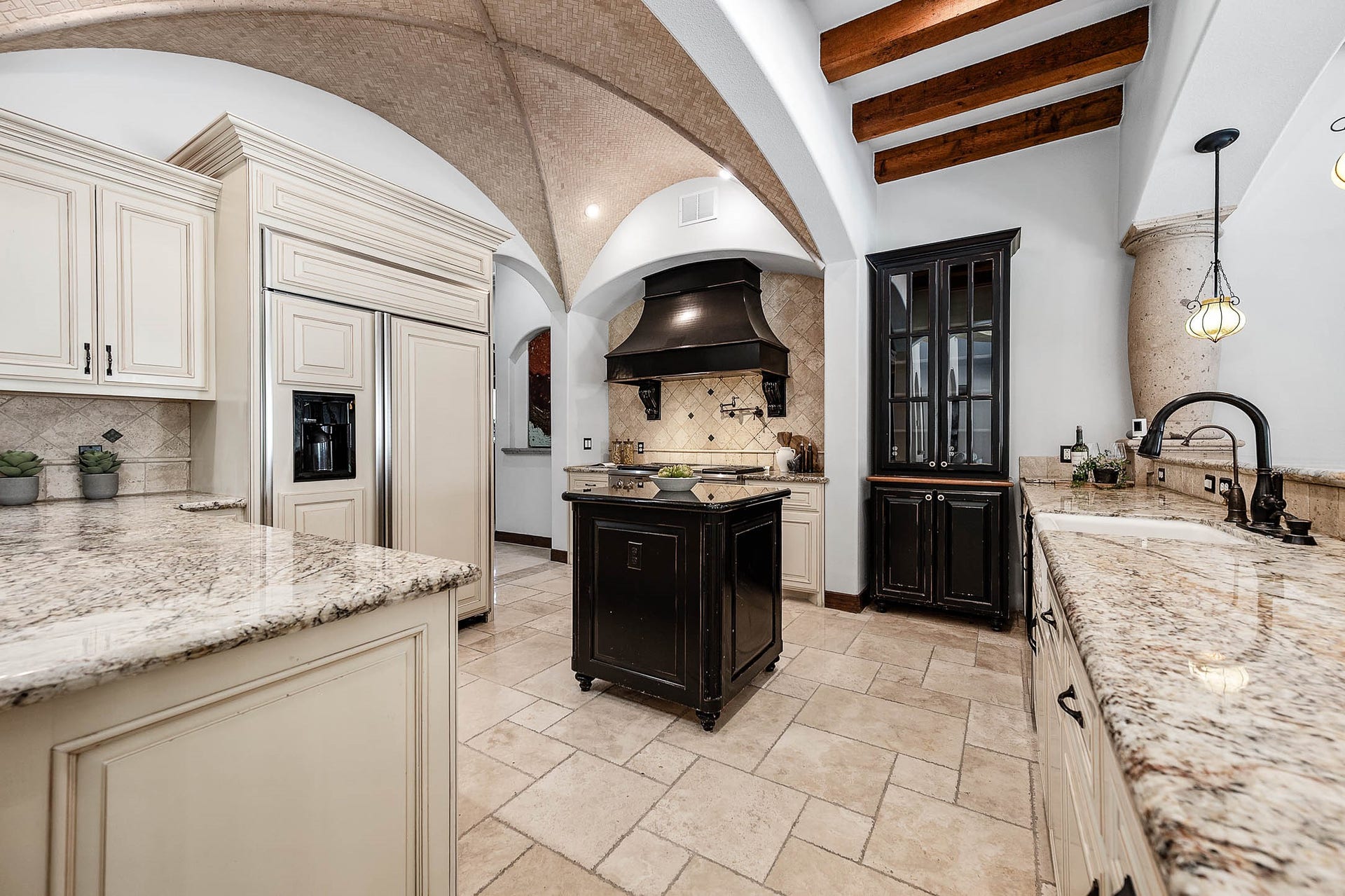 A groin-vaulted brick ceiling, a built-in refrigerator, and granite countertops complete the kitchen.