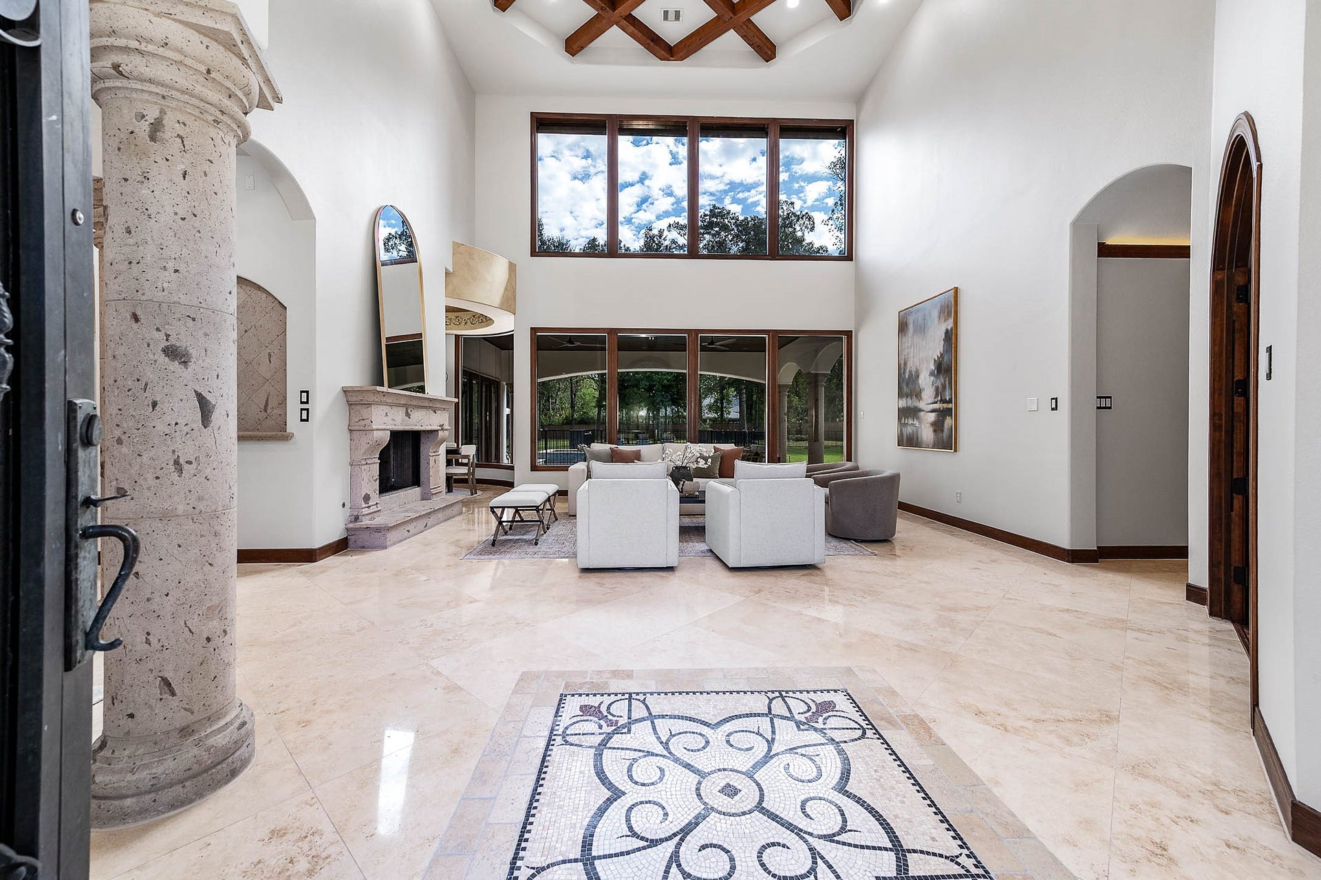 The dramatic 24-foot foyer showcases an intricate mosaic medallion set into polished travertine floors and a Cantera stone column.
