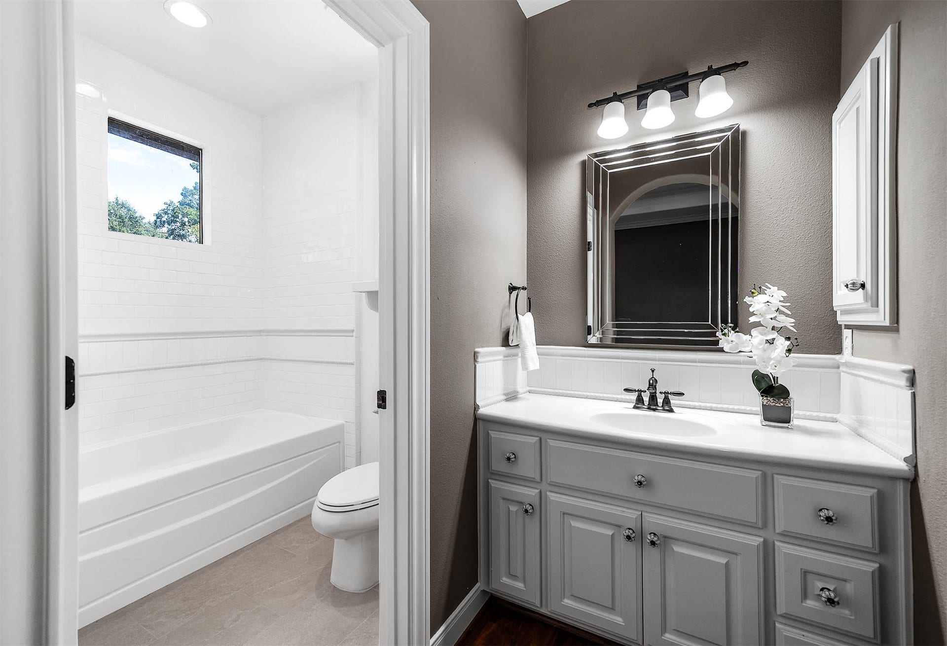 The ensuite bath features a single vanity and a tub/shower combination finished in fresh white tile.