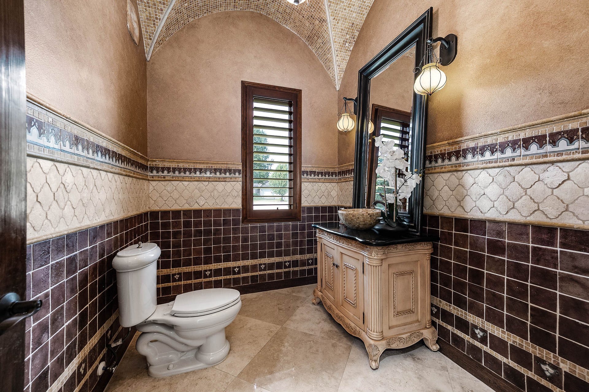 The powder room features a groin-vaulted tile ceiling, a furniture-style vanity, and decorative tile wainscoting.