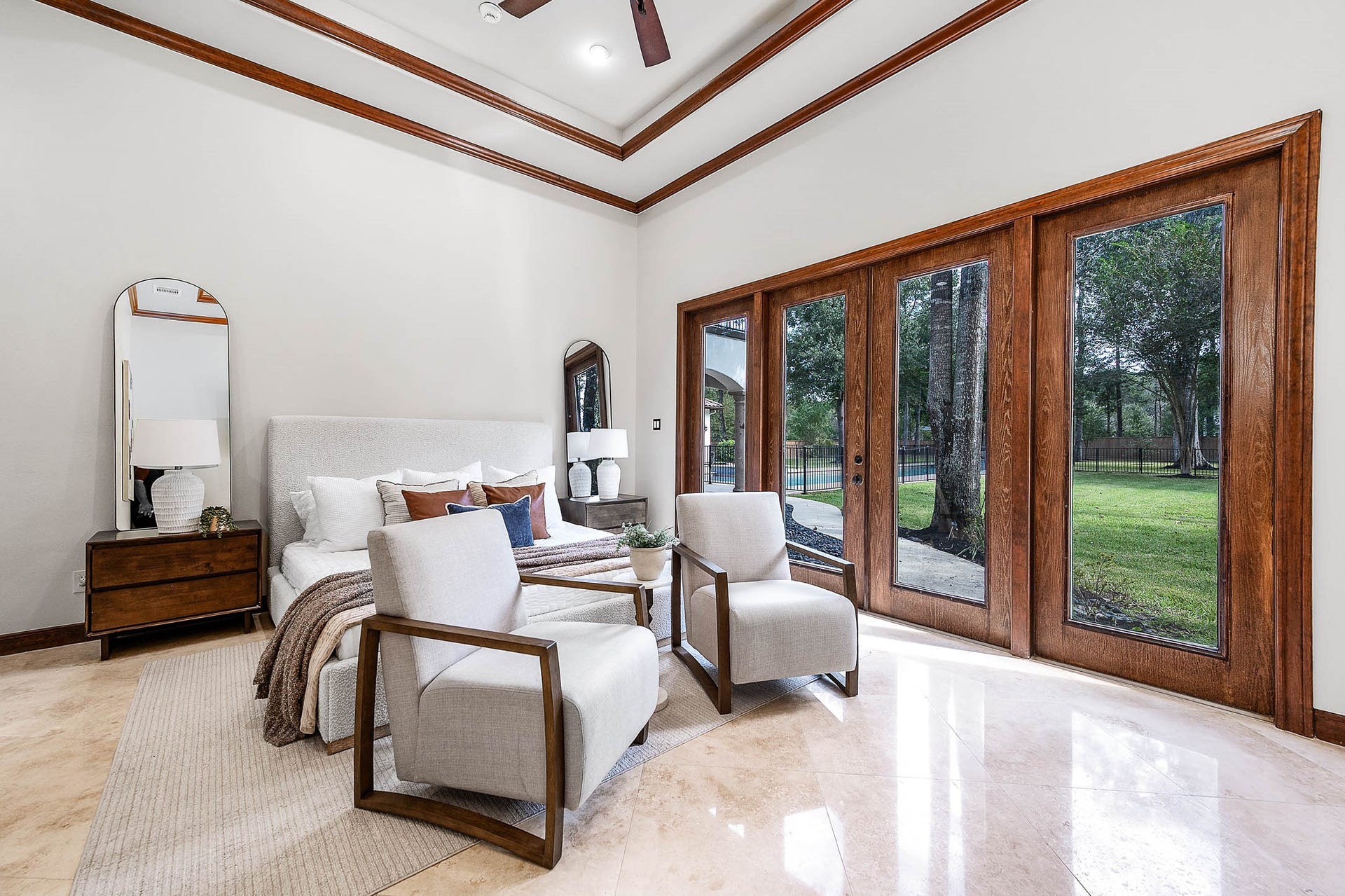 Polished stone floors and expansive views of the wooded backyard complete the primary bedroom.