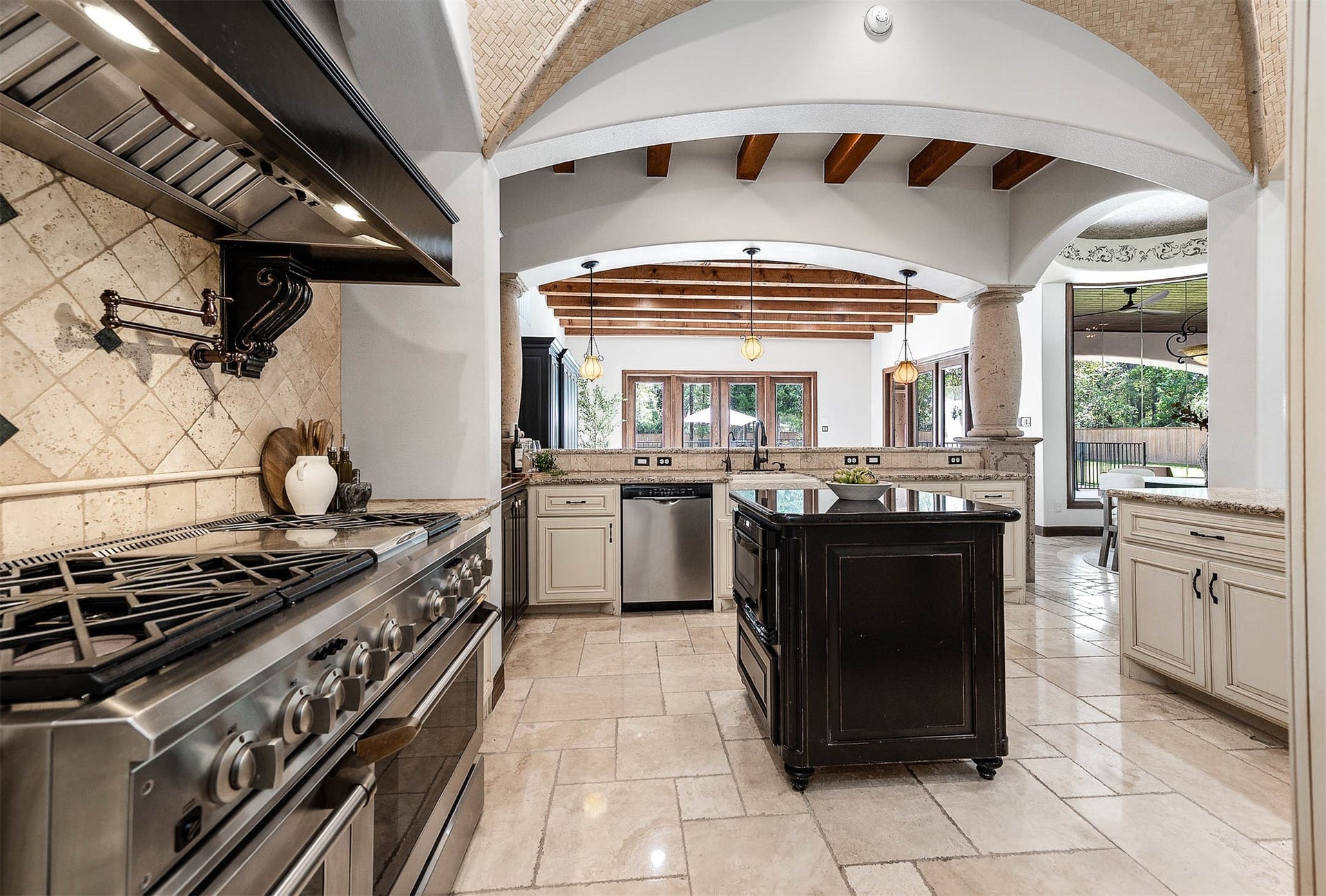 A gas range with double ovens, a pot filler, and a custom vent hood anchors the kitchen.