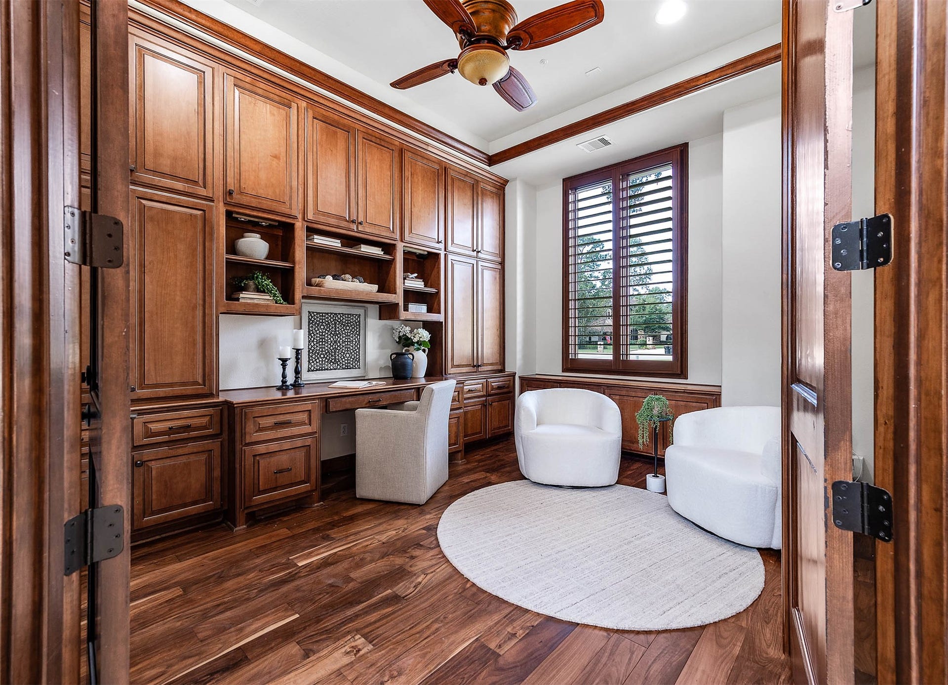 The home office off the front of the home features rich wood-paneled built-ins, a custom desk, and hardwood floors.
