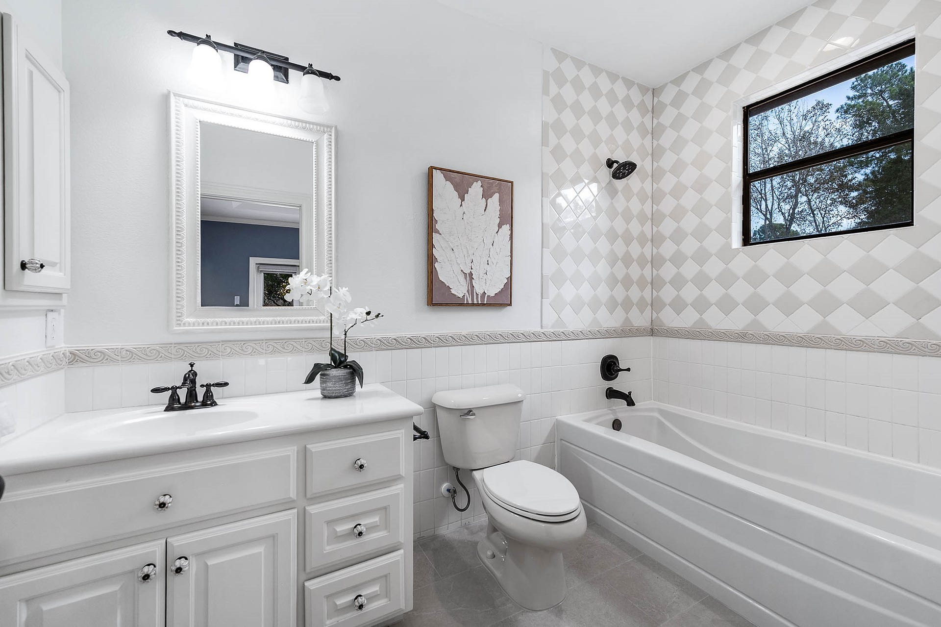 This secondary bath features new diamond-pattern tile, a single vanity, and a tub/shower combination.