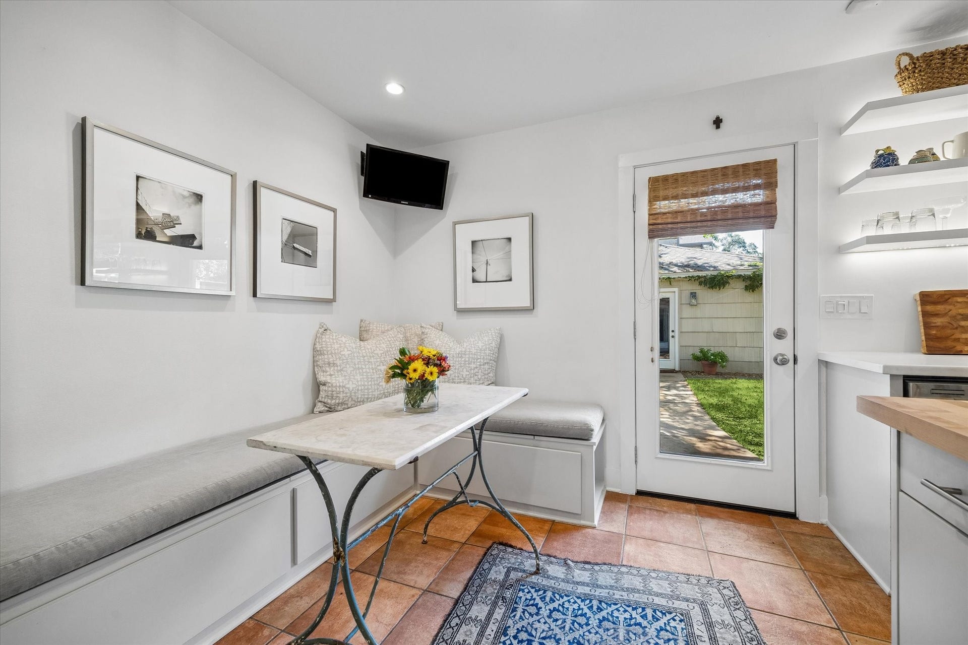 Charming breakfast nook with built-in seating and a cozy atmosphere, leading to a lush backyard through a glass door. Perfect for morning coffee or casual meals.