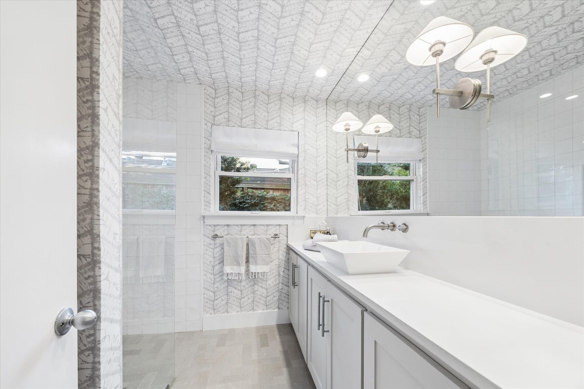 The secondary bathroom features sleek fixtures and contemporary finishes with a curbless shower with frameless glass and Ann Sacks tile.