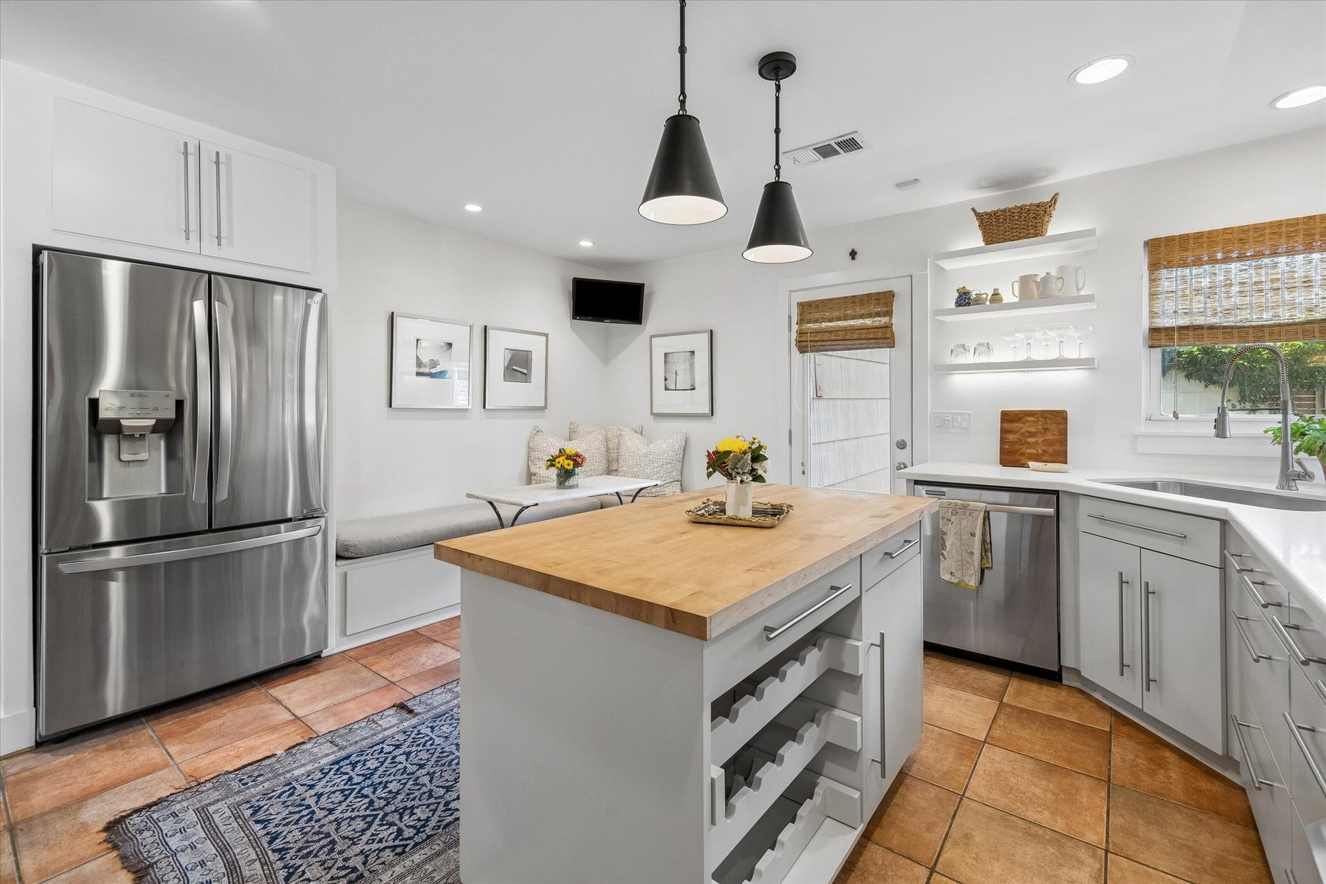 Charming kitchen with modern stainless-steel appliances, a cozy breakfast nook, and a central island perfect for meal prep & wine storage.