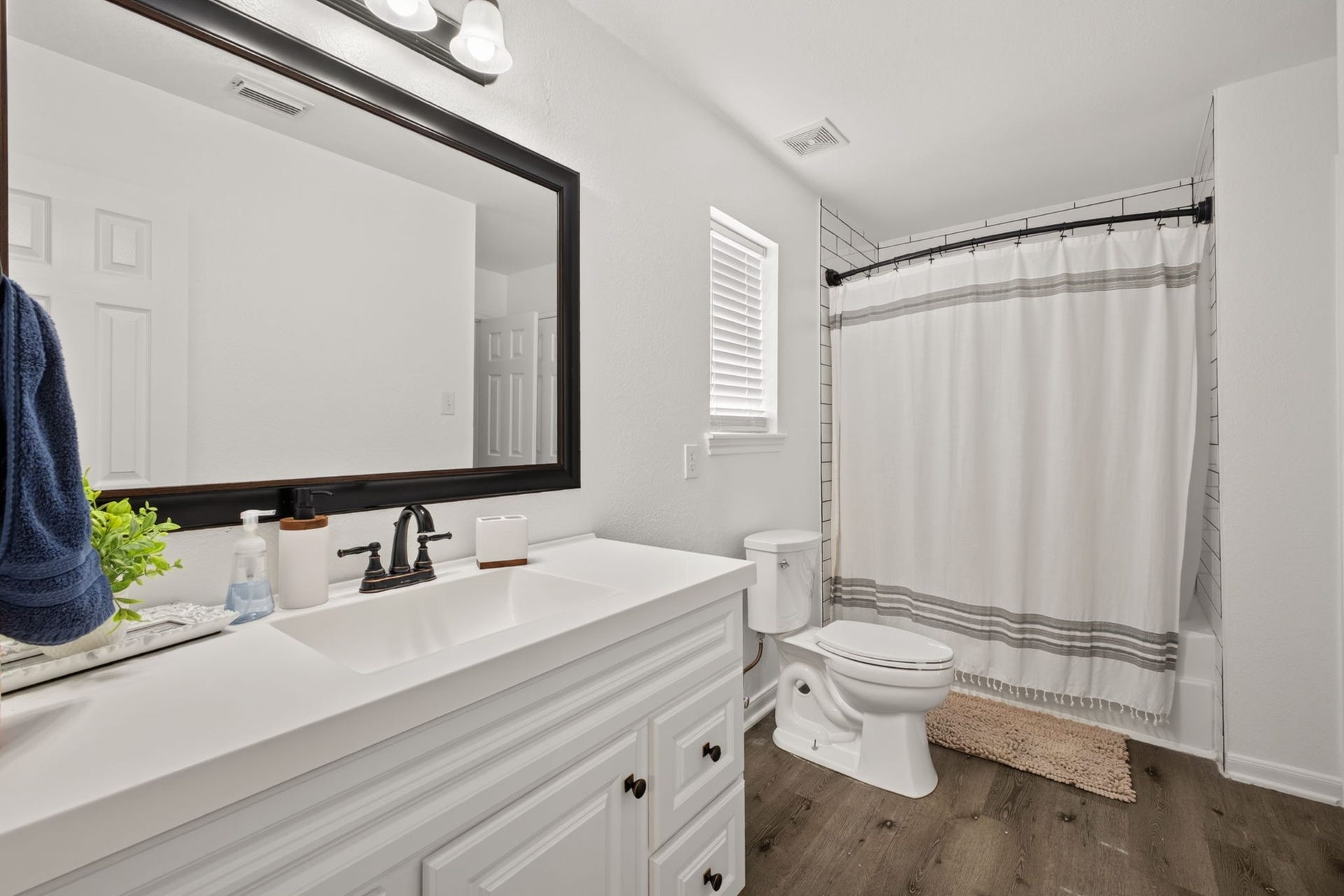 17307 Thicket Hollow Lane, Cypress, TX 77429 This updated bathroom features a modern design with a large vanity, dark-framed mirror, and sleek fixtures.