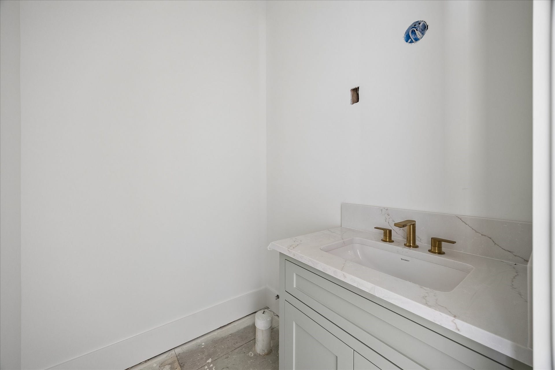 915 Lamonte Lane, Houston, TX 77018 Rectangular basin, veined counter and brass tone faucet create a warm contrast against the light vanity and walls. Enclosed cabinet storage sits below the basin, keeping daily supplies close at hand. Mirror and final lighting installation remain in progress.