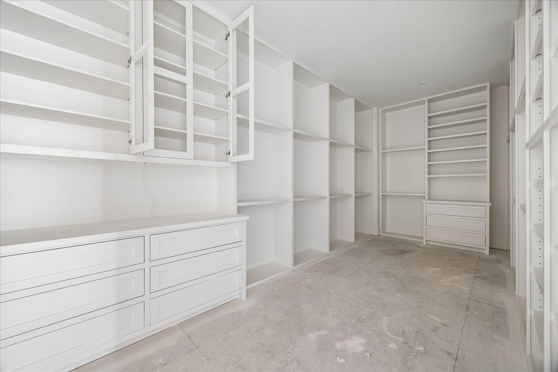 915 Lamonte Lane, Houston, TX 77018 Custom closet cabinetry combines open shelves, drawer banks and tall compartments for different storage needs. Storage extends around the perimeter and uses the full wall height, leaving a central passage through the room. Flooring and final hardware remain in progress.