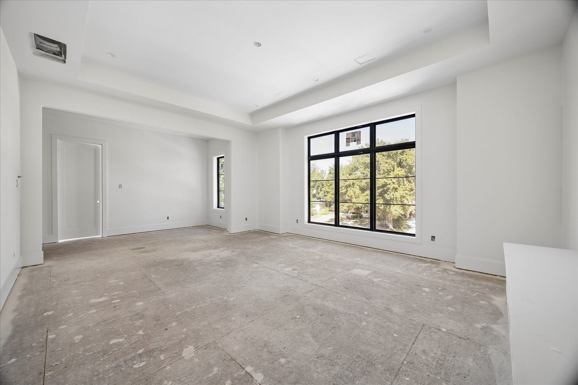 915 Lamonte Lane, Houston, TX 77018 Large windows and a recessed ceiling give this upper level room a bright, open character. A wall recess adds definition beside the doorway without closing the room off. The view shows the room before flooring and lighting installation are complete.