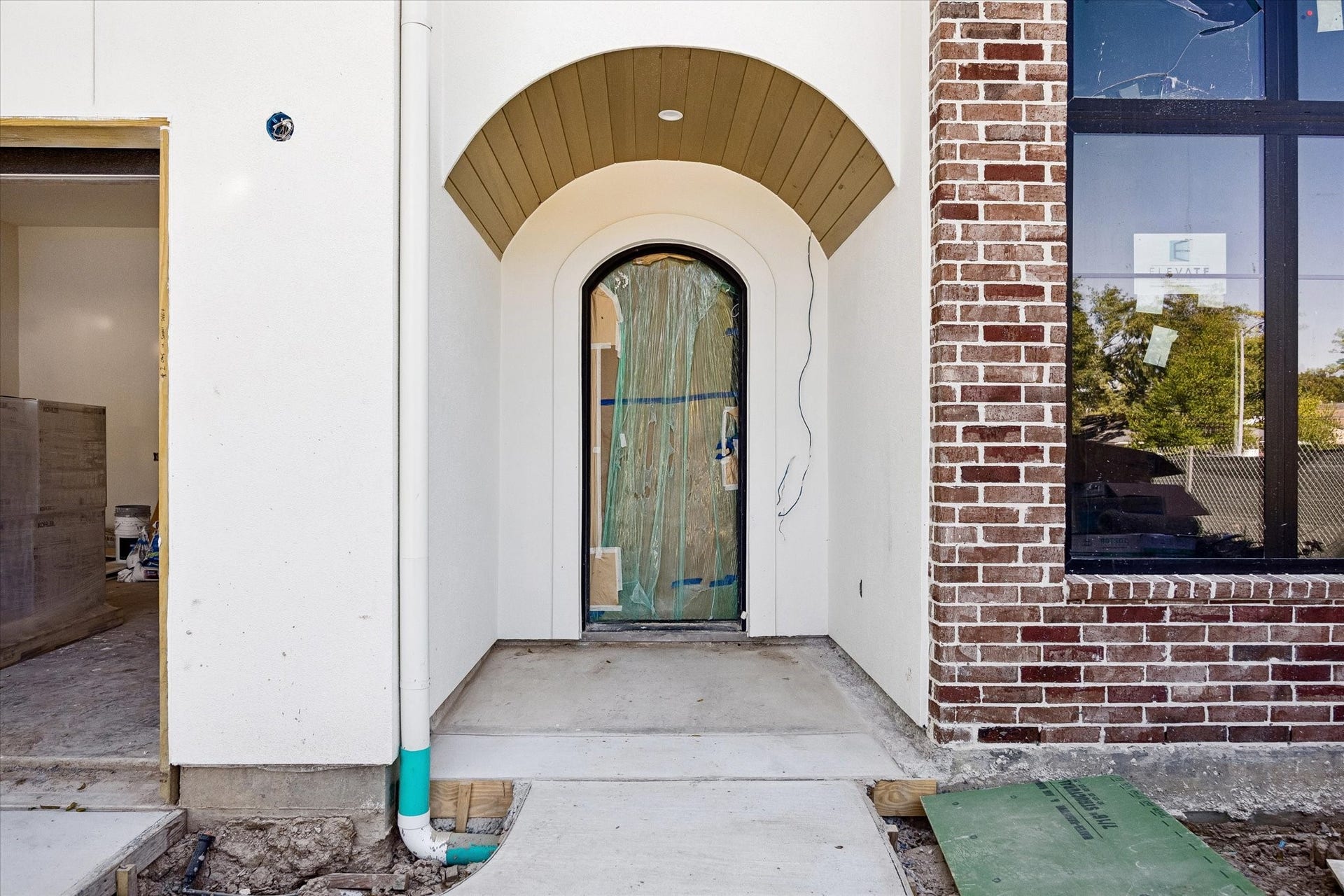 915 Lamonte Lane, Houston, TX 77018 Recessed arches shelter the front door beneath a stained beadboard porch ceiling. Brick texture, a tall black framed window and the curved entry opening layer the exterior materials at the approach. Protective covering remains on the door during construction.