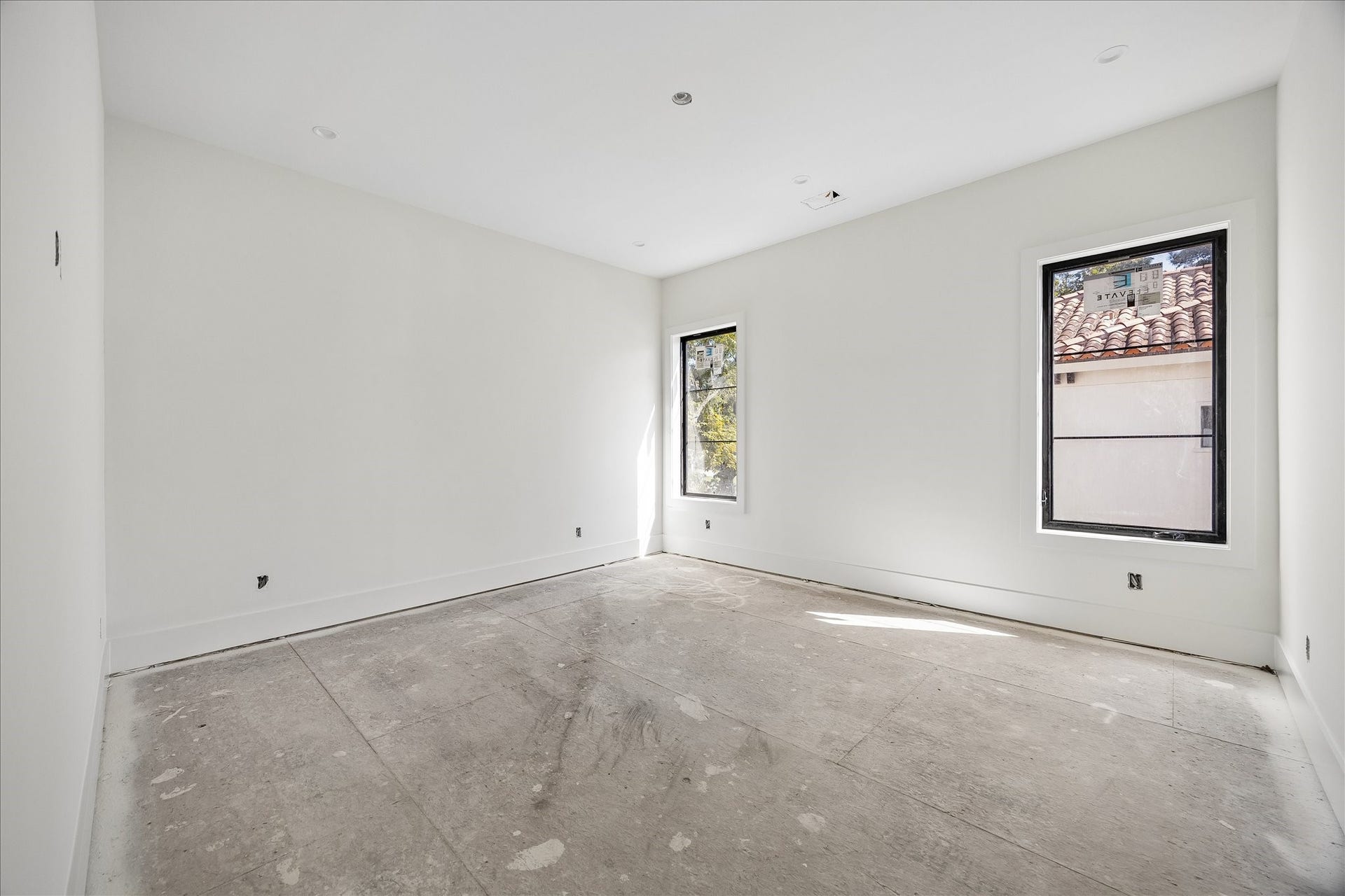 915 Lamonte Lane, Houston, TX 77018 2 tall windows brighten this room while preserving a broad wall area between the openings. Deep baseboards and simple door trim continue the home's restrained interior detailing. The photograph shows the room before final flooring and fixture installation.