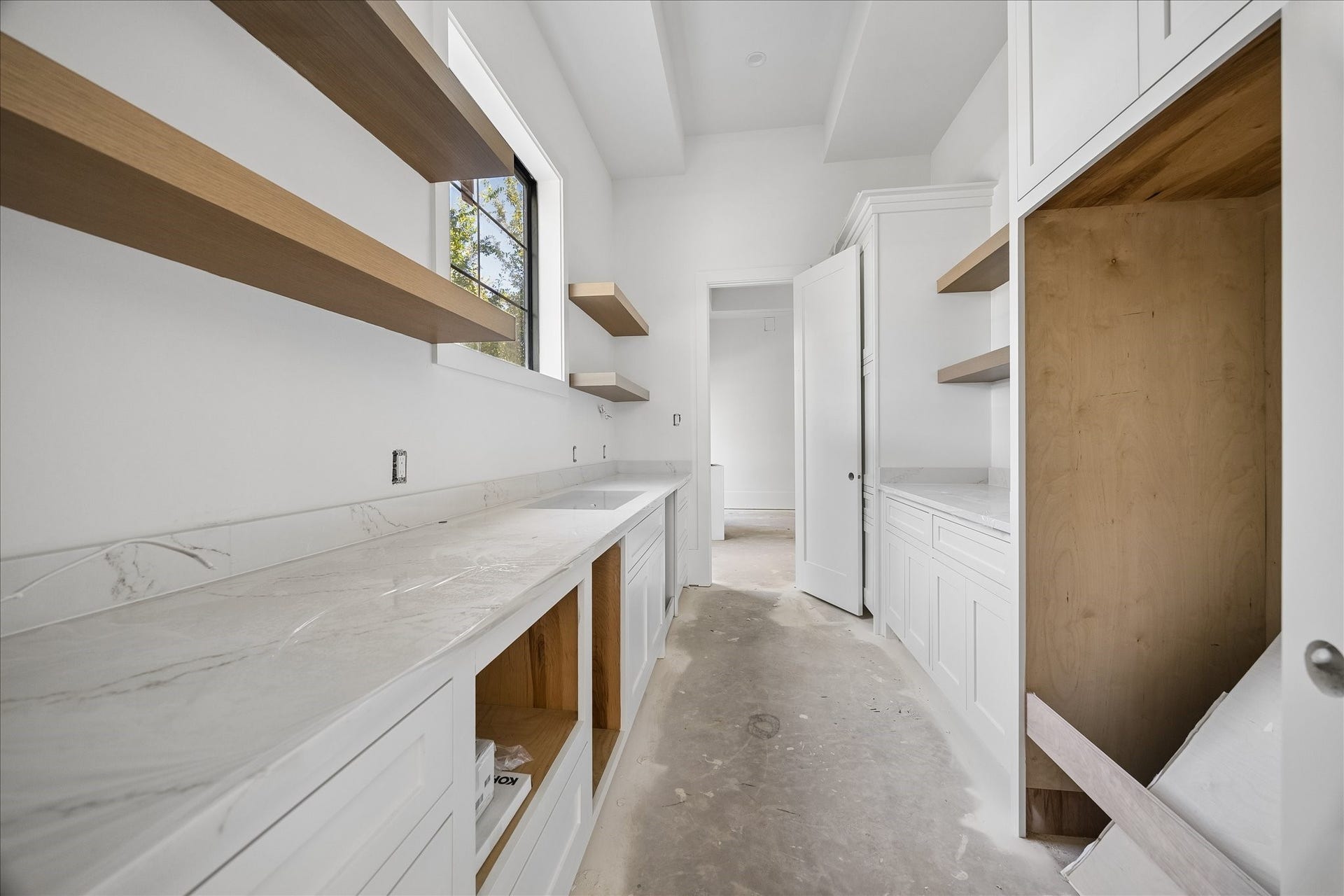 915 Lamonte Lane, Houston, TX 77018 Butler's pantry provides a separate counter and storage zone between the dining room and kitchen. Long work surfaces, open wood shelves, lower drawers and tall cabinetry add capacity for preparation and serving while keeping supplies outside the main living area.