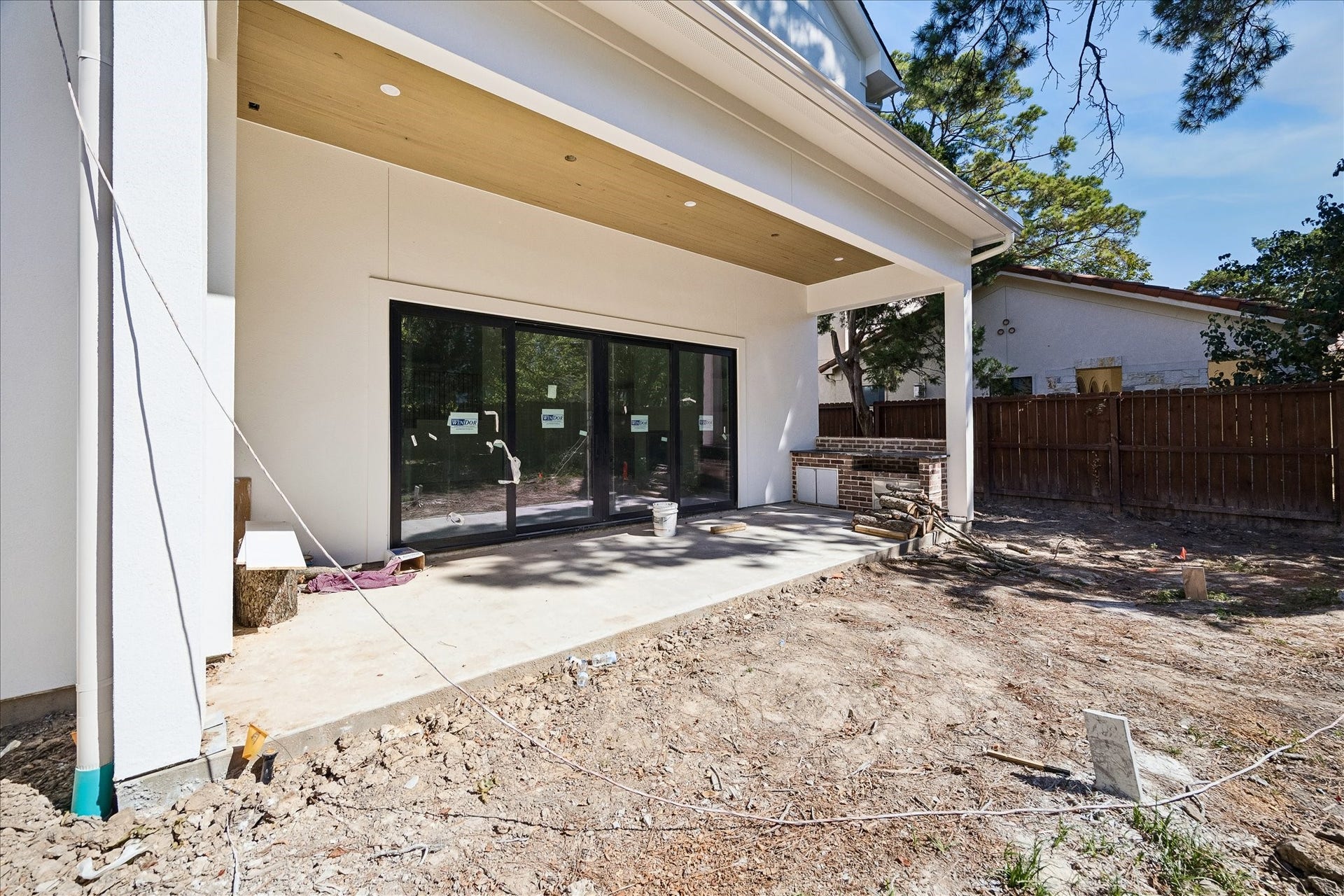 915 Lamonte Lane, Houston, TX 77018 Covered rear porch pairs a stained beadboard ceiling and recessed lights with broad doors to the living room. The brick counter structure defines the planned outdoor kitchen. A 40 inch natural gas grill and sink are specified; installation and yard work remain in progress.