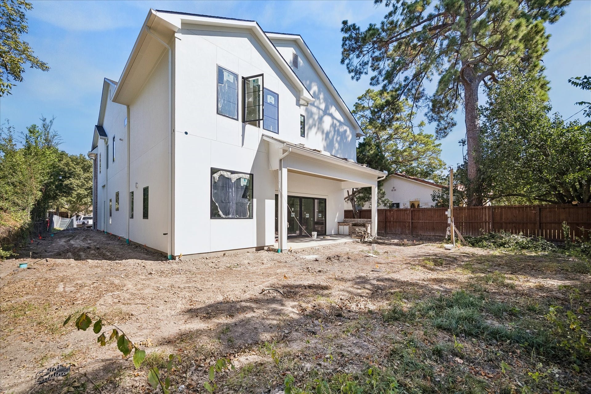 915 Lamonte Lane, Houston, TX 77018 Rear elevation views place the covered porch beside the open backyard and side yard. Broad windows and sliding doors connect the interior to the outdoor space. Plans route utilities along the side to preserve backyard flexibility; landscaping remains in progress.
