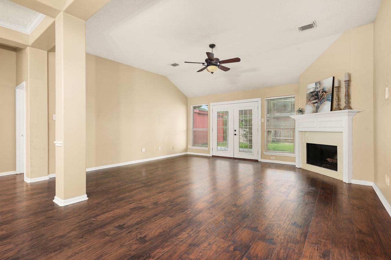 3802 Oakwilde Circle, La Porte, TX 77571 Spacious Living Area with High Ceiling, Beautiful Wood-Look Flooring, Fireplace, and French Doors Leading to the Covered Patio.