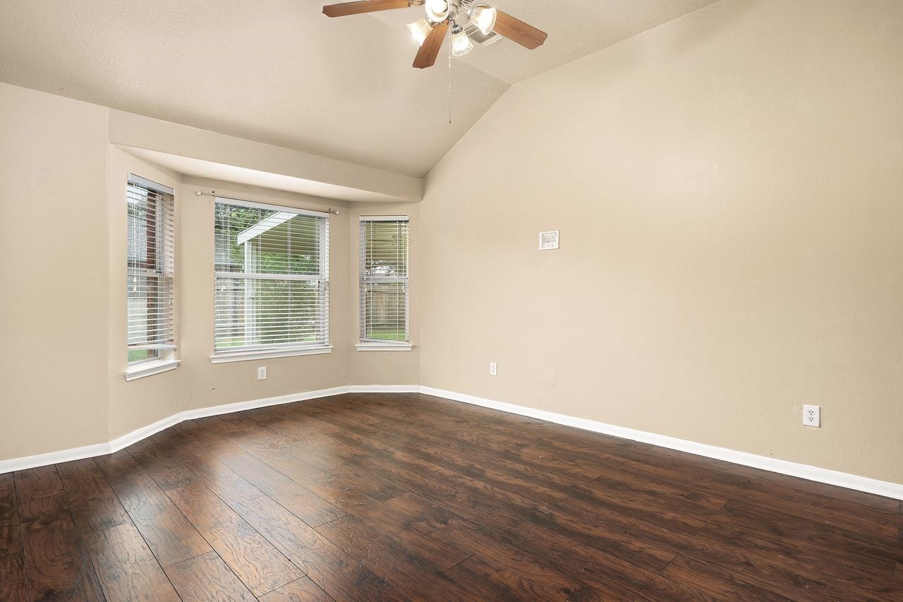 3802 Oakwilde Circle, La Porte, TX 77571 Spacious Primary Bedroom Features Beautiful Wood-Look Flooring, High Ceiling, and a Charming Bay Window That Brings in Plenty of Natural Light.