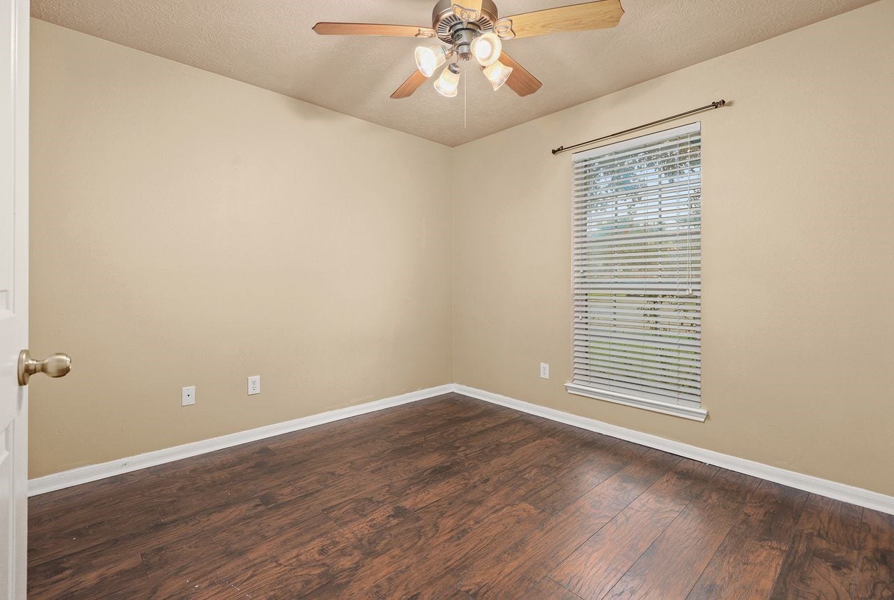 3802 Oakwilde Circle, La Porte, TX 77571 Secondary Bedroom Features Wood-Look Flooring, Ceiling Fan, and Window with Faux Wood Blinds.