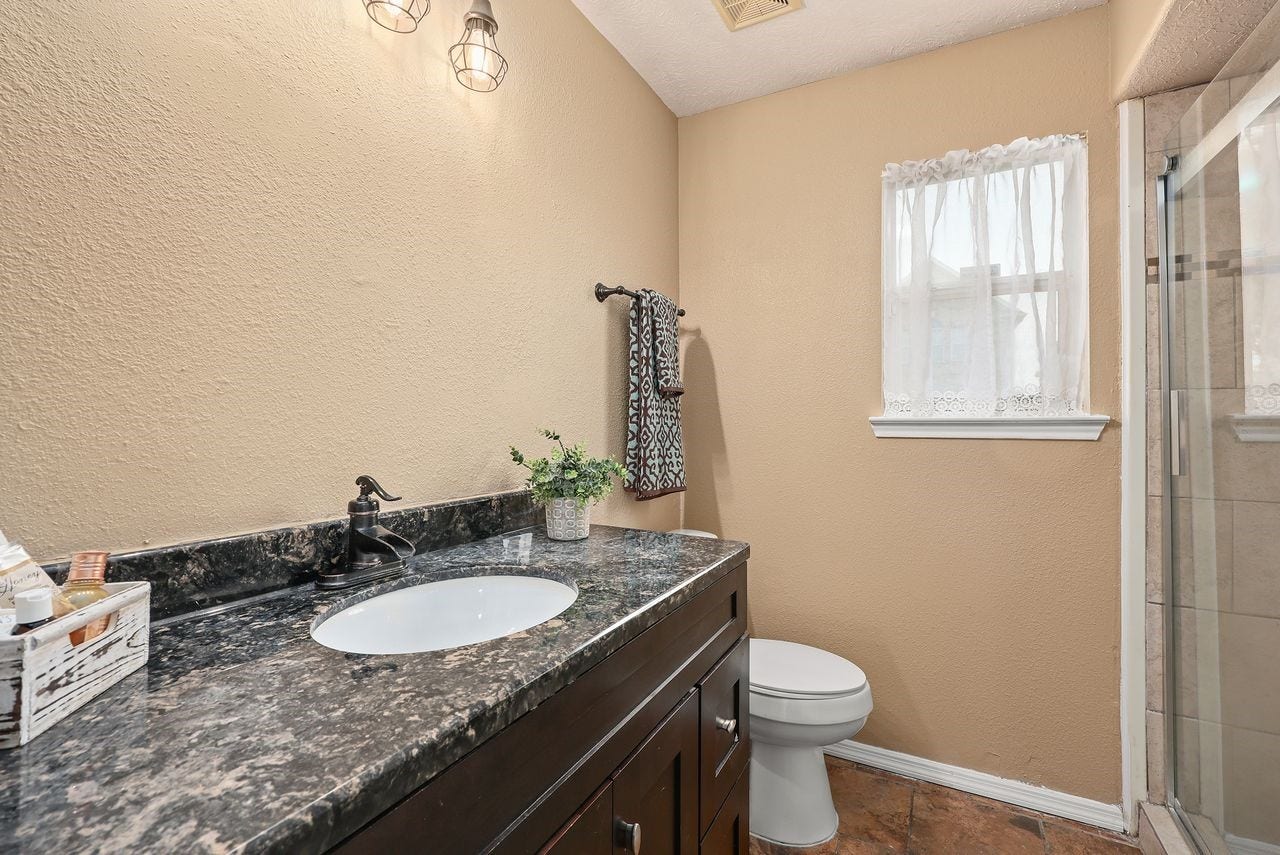 3802 Oakwilde Circle, La Porte, TX 77571 Nicely Appointed Guest Bath Features a Beautiful Granite Countertop, Dark Wood Vanity, Updated Fixtures, and an Oversized Tiled Shower with Glass Enclosure.