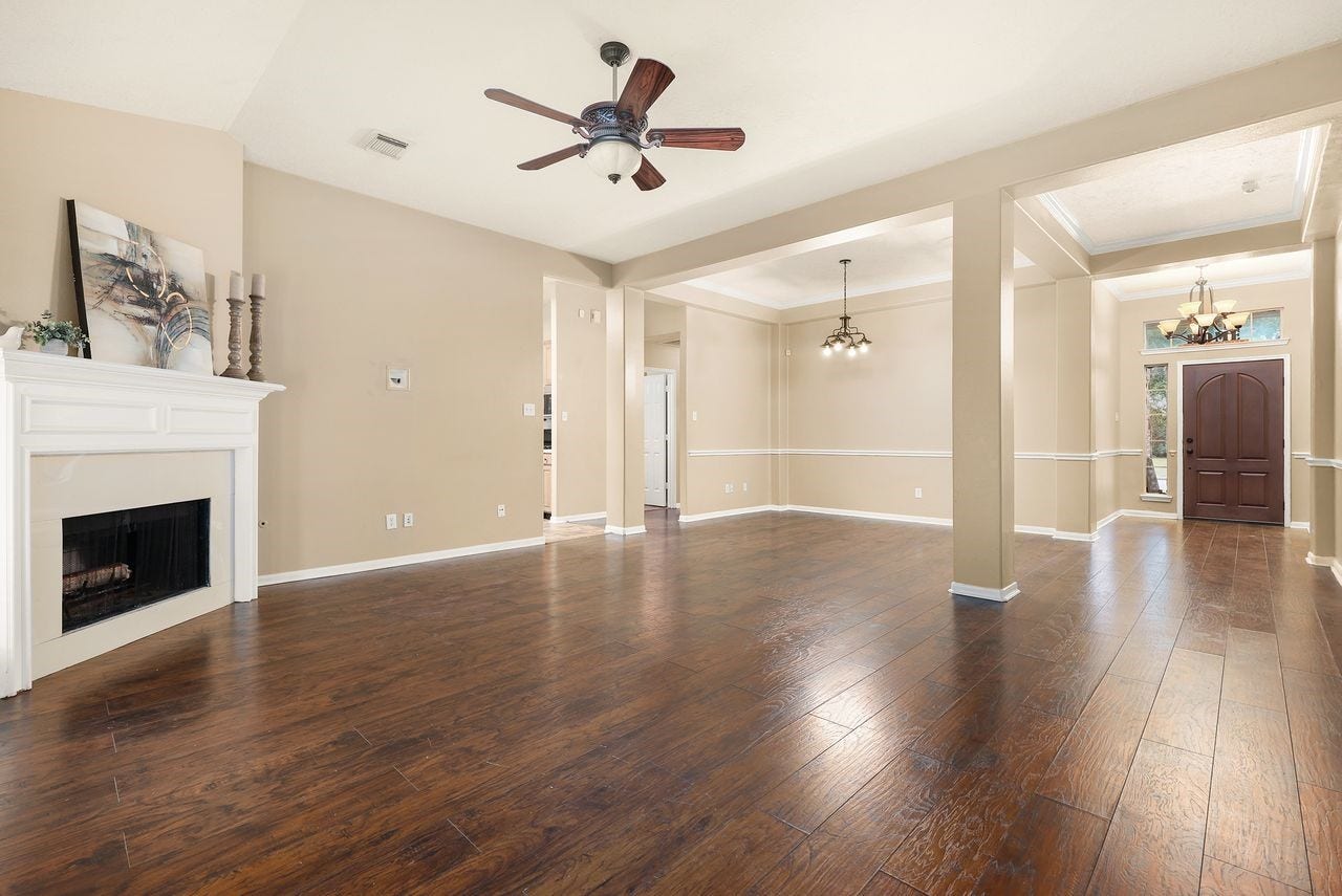 3802 Oakwilde Circle, La Porte, TX 77571 Open Living and Dining Area Features Rich Wood-Look Flooring, High Ceilings, Decorative Molding, and a Cozy Fireplace.