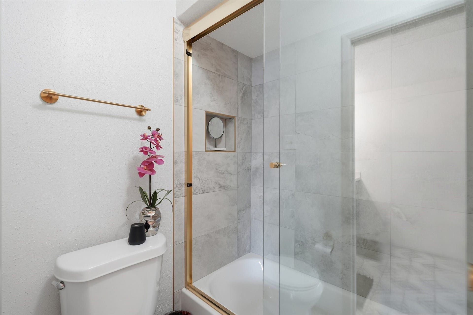 Beautiful remodeled shower/tub combination with sleek gold hardware.
