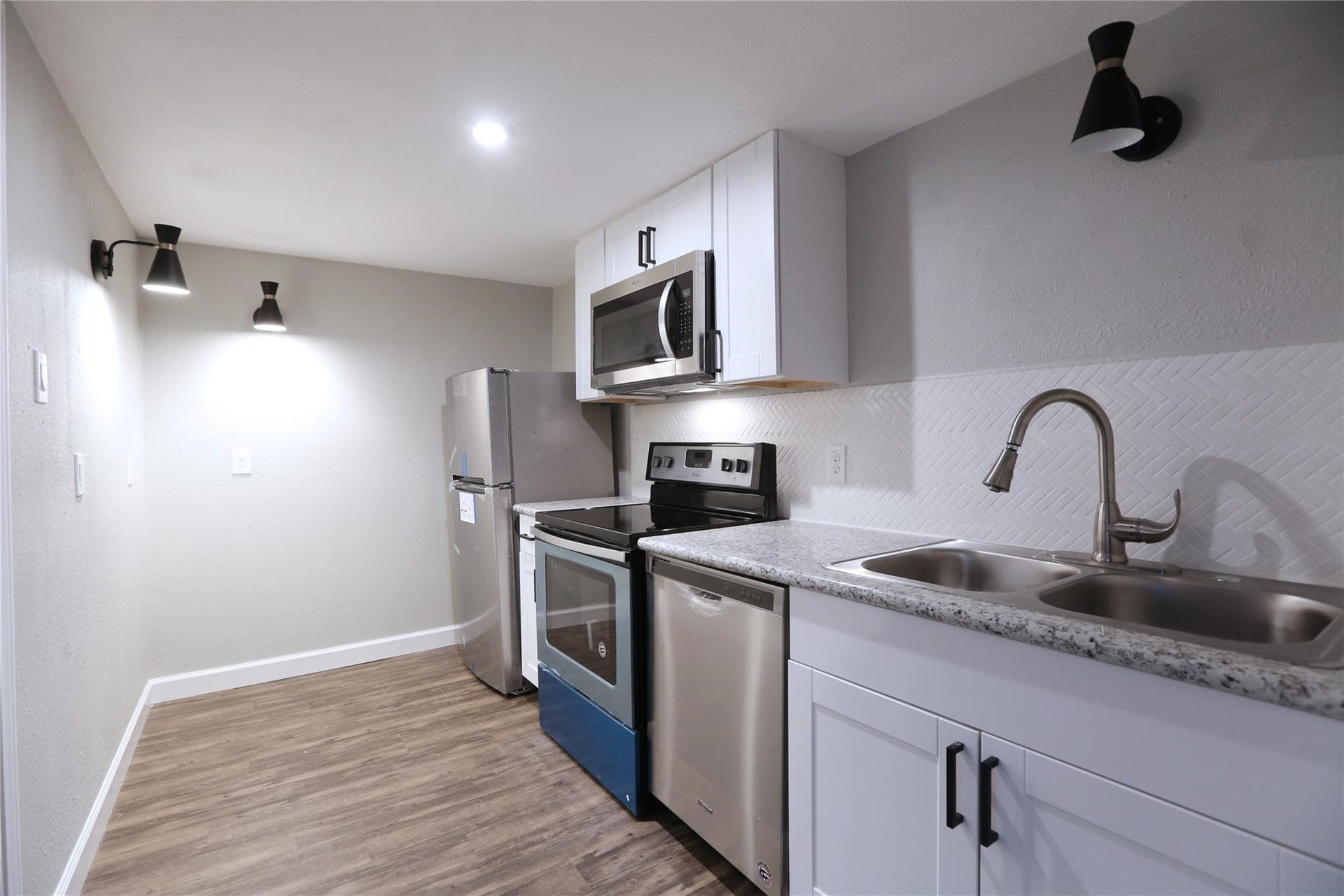 5917 1/2 Sherman Street, #1, Houston, TX 77011 Open space between the living room and kitchen which comes with stove, refrigerator, oven, microwave and a stacked washer & dryer on the side.