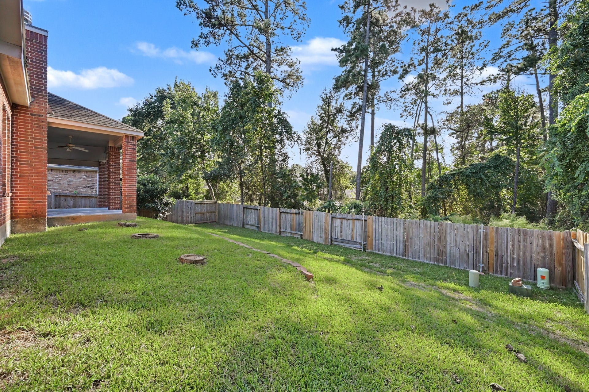 Spacious, fully fenced backyard with lush green lawn, mature trees, wooded backdrop and no rear neighbors, offering privacy and peaceful views!