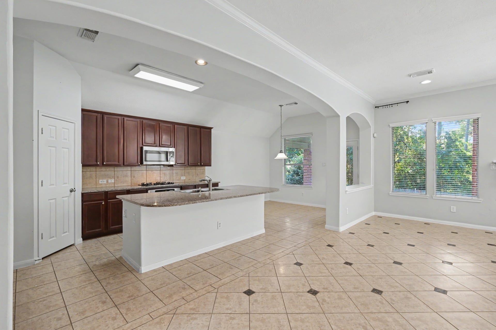Spacious island kitchen featuring granite countertops, rich wood cabinetry, breakfast bar with sink, walk-in pantry and adjoining breakfast area.