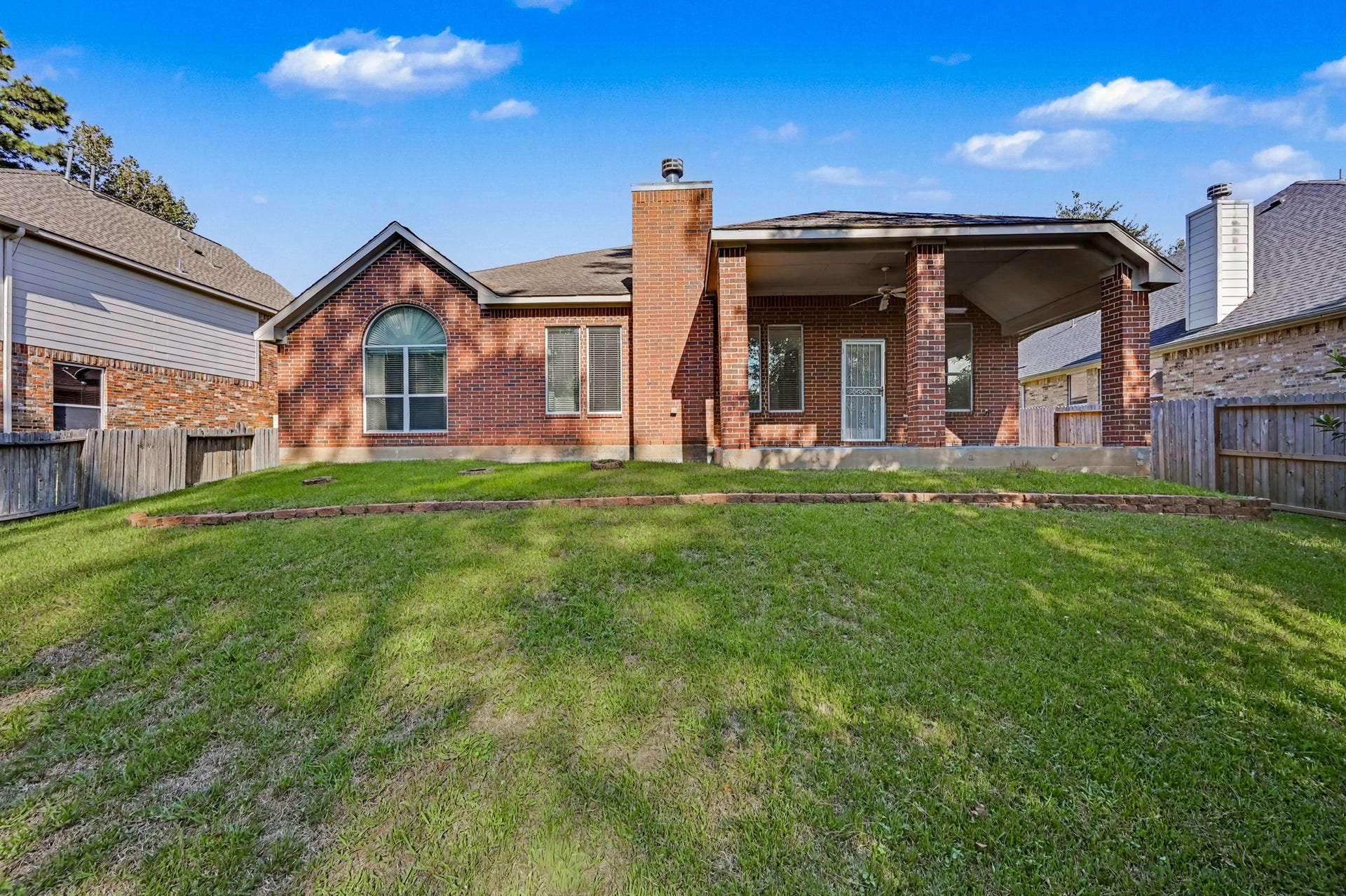 Spacious, fully fenced backyard featuring a large covered patio with ceiling fan, perfect for outdoor entertaining and relaxation!
