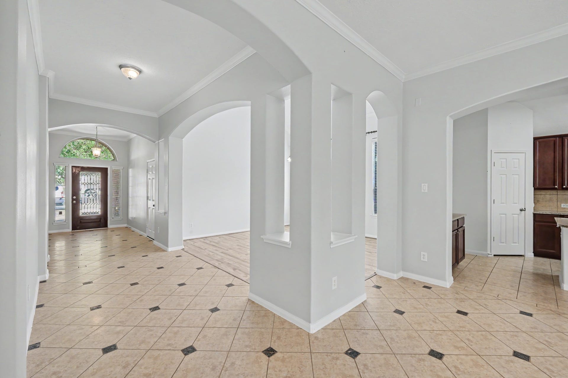 Spacious open floor plan featuring decorative tile flooring, crown molding and elegant archways connecting the living, dining and kitchen areas.
